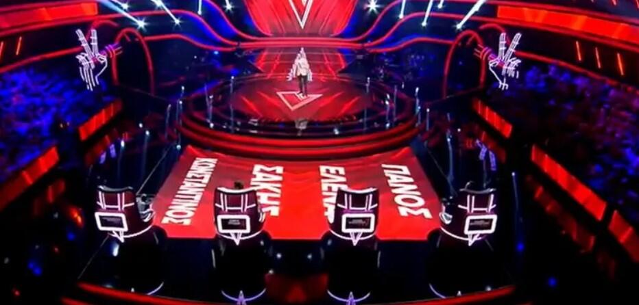 Πανοραμική άποψη της σκηνής του The Voice Greece με τις καρέκλες των κριτών και διαγωνιζόμενο στο κέντρο.