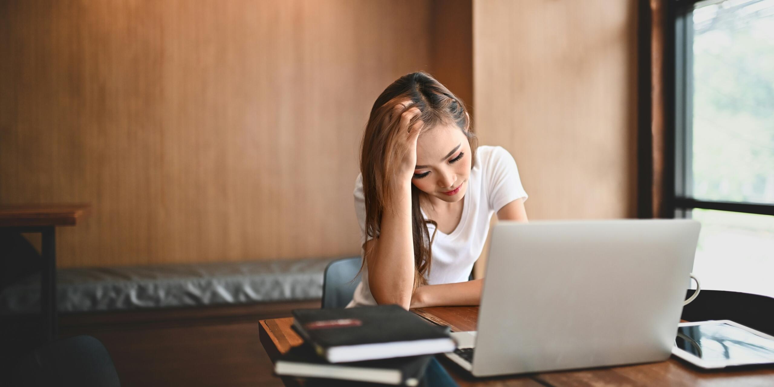 Μαθήτρια με άγχος μπροστά από laptop και σημειωματάρια στο γραφείο της