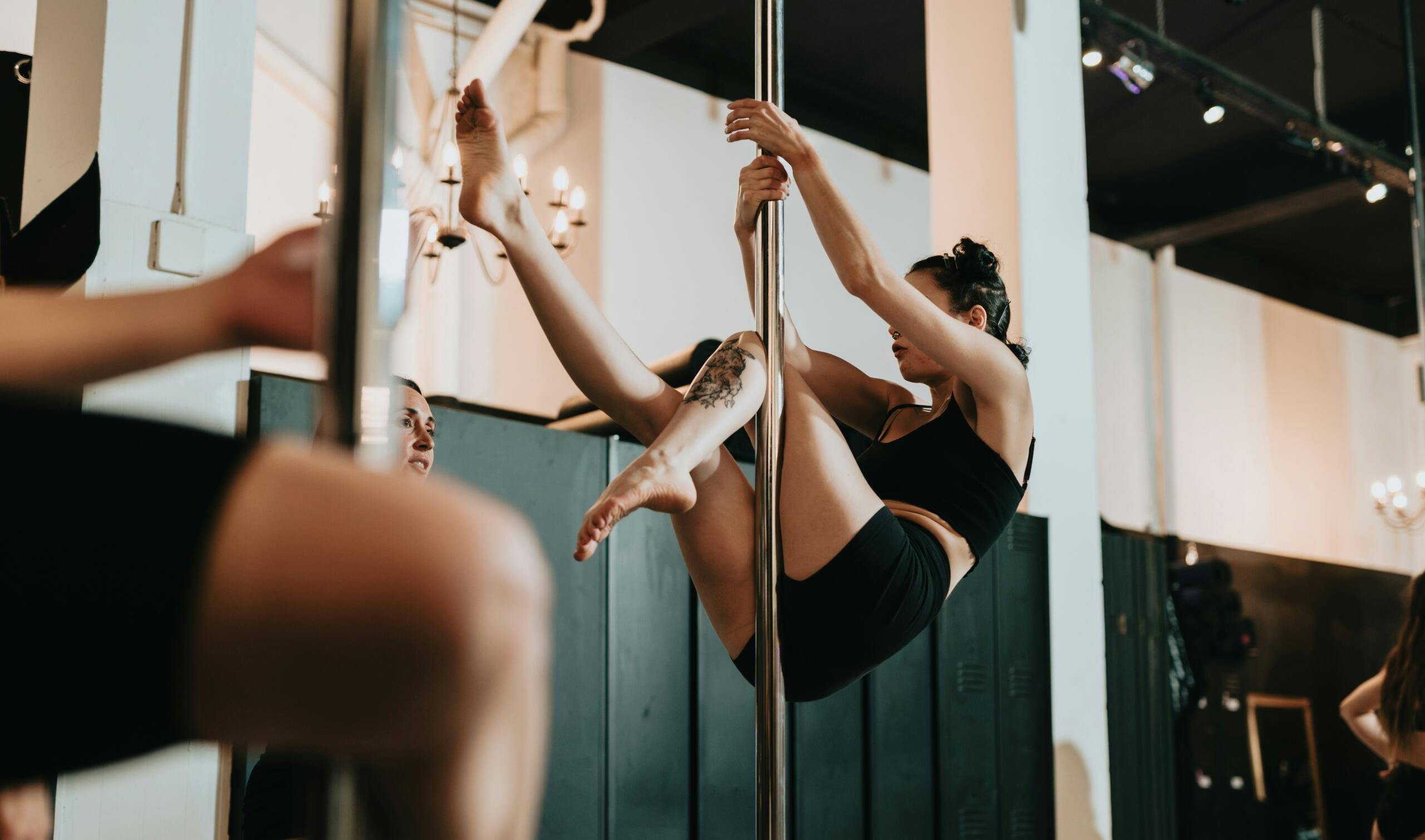 Γυναίκα κάνει pole dancing σε αίθουσα εκγύμνασης.