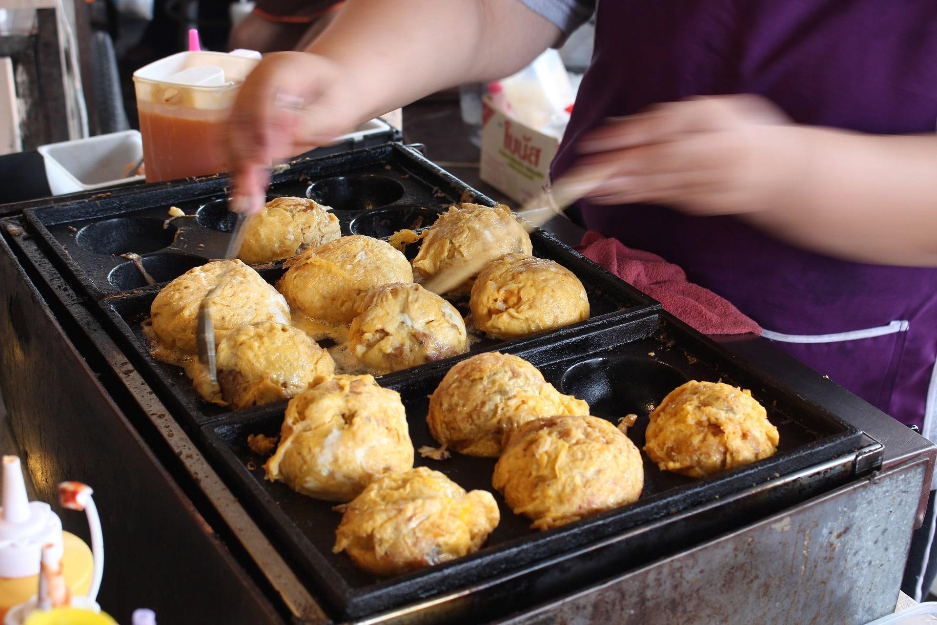Seorang koki sedang memasak takoyaki. Sebuah pekerjaan yang cukup menyita waktu karena setiap takoyaki harus dibalik secara manual 