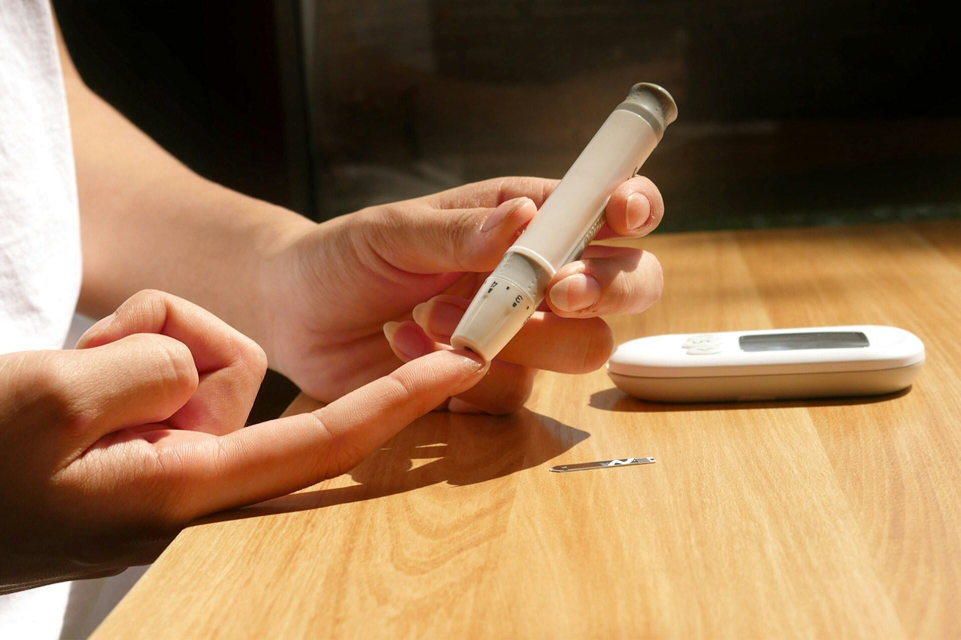 Person using a finger prick blood testing device on a fingertip