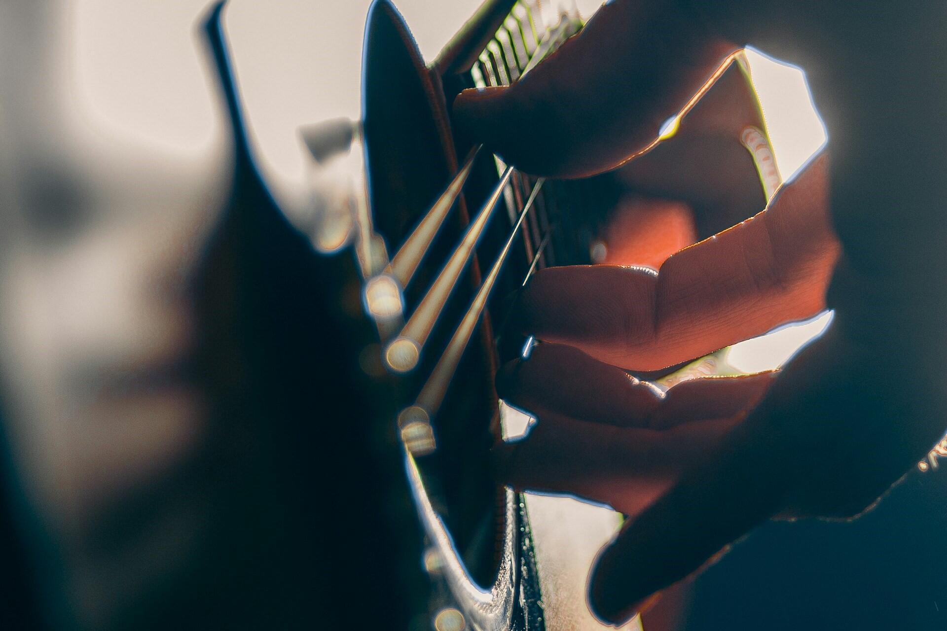 Close-up of fingers playing guitar strings