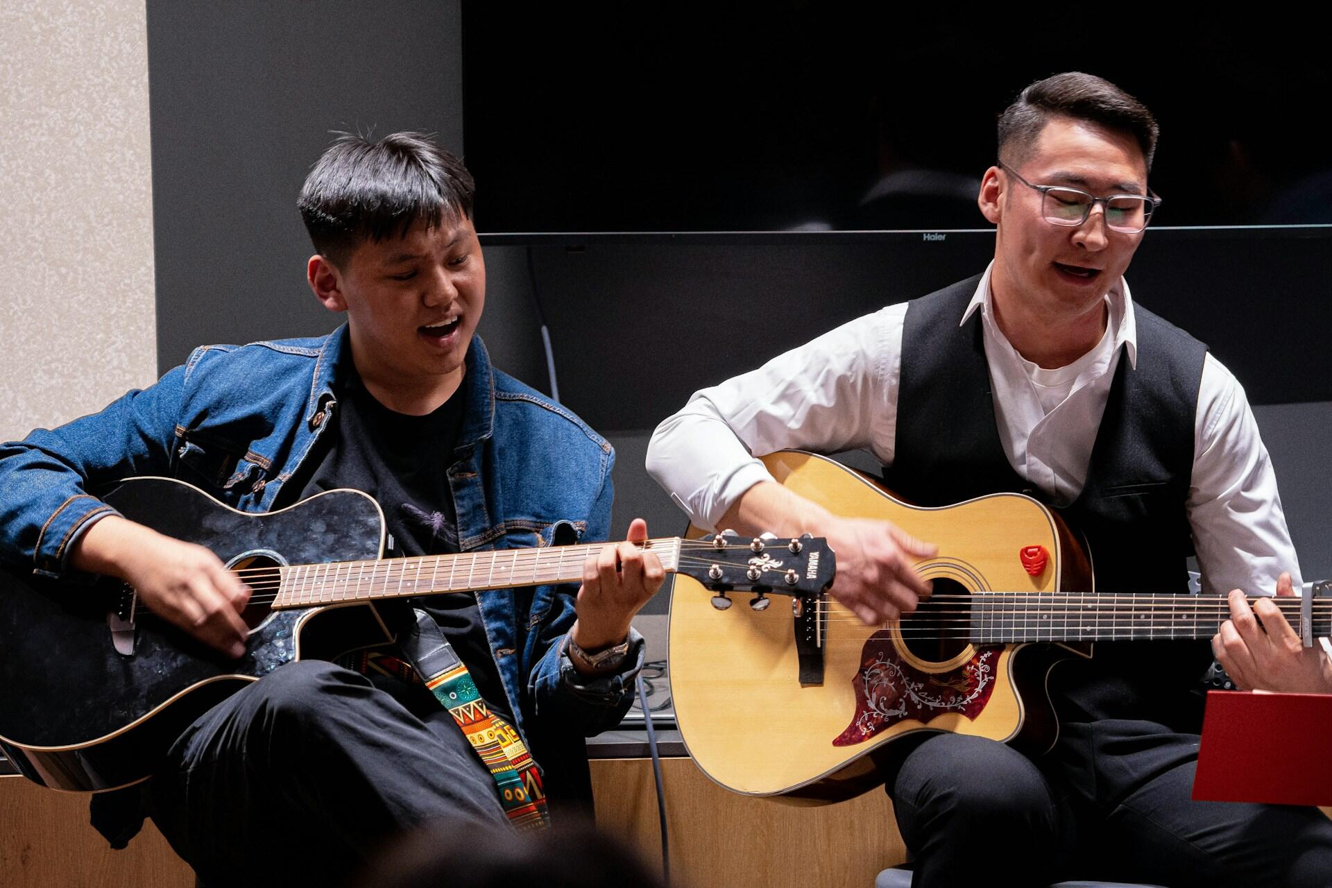 Two musicians playing acoustic guitars together