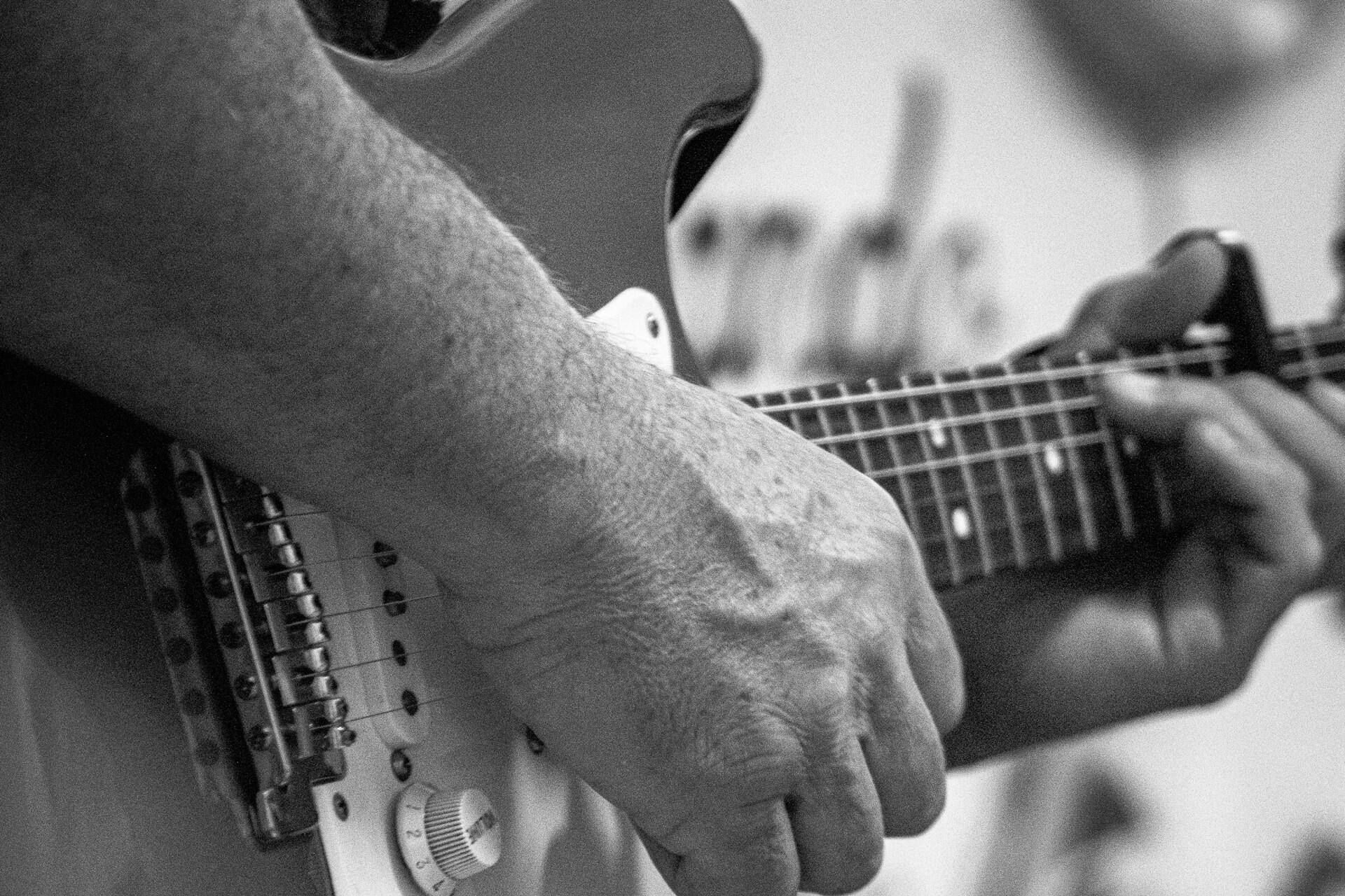 Close-up of hands playing an electric guitar in black and white