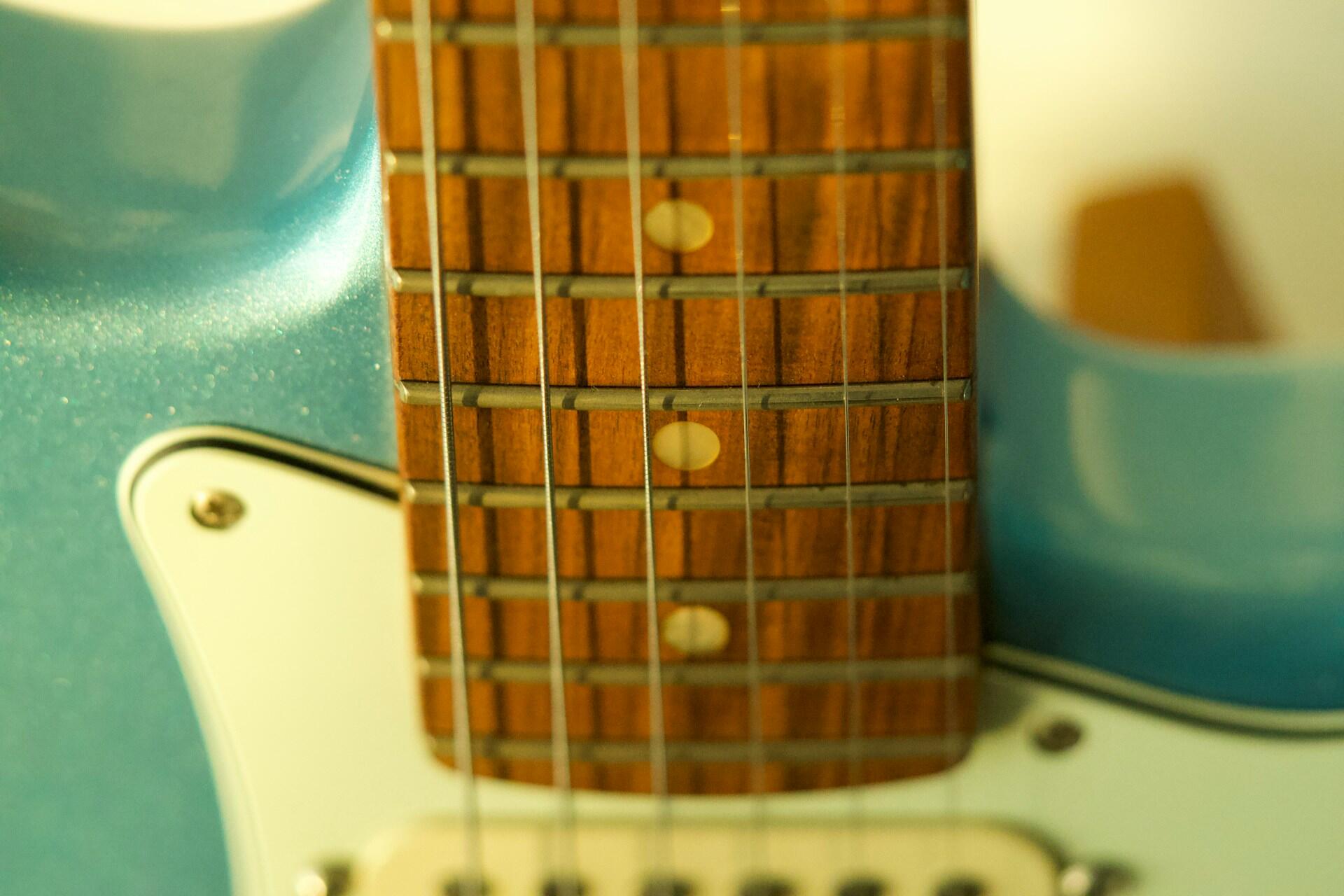 Close-up of the strings and frets on an electric guitar fretboard