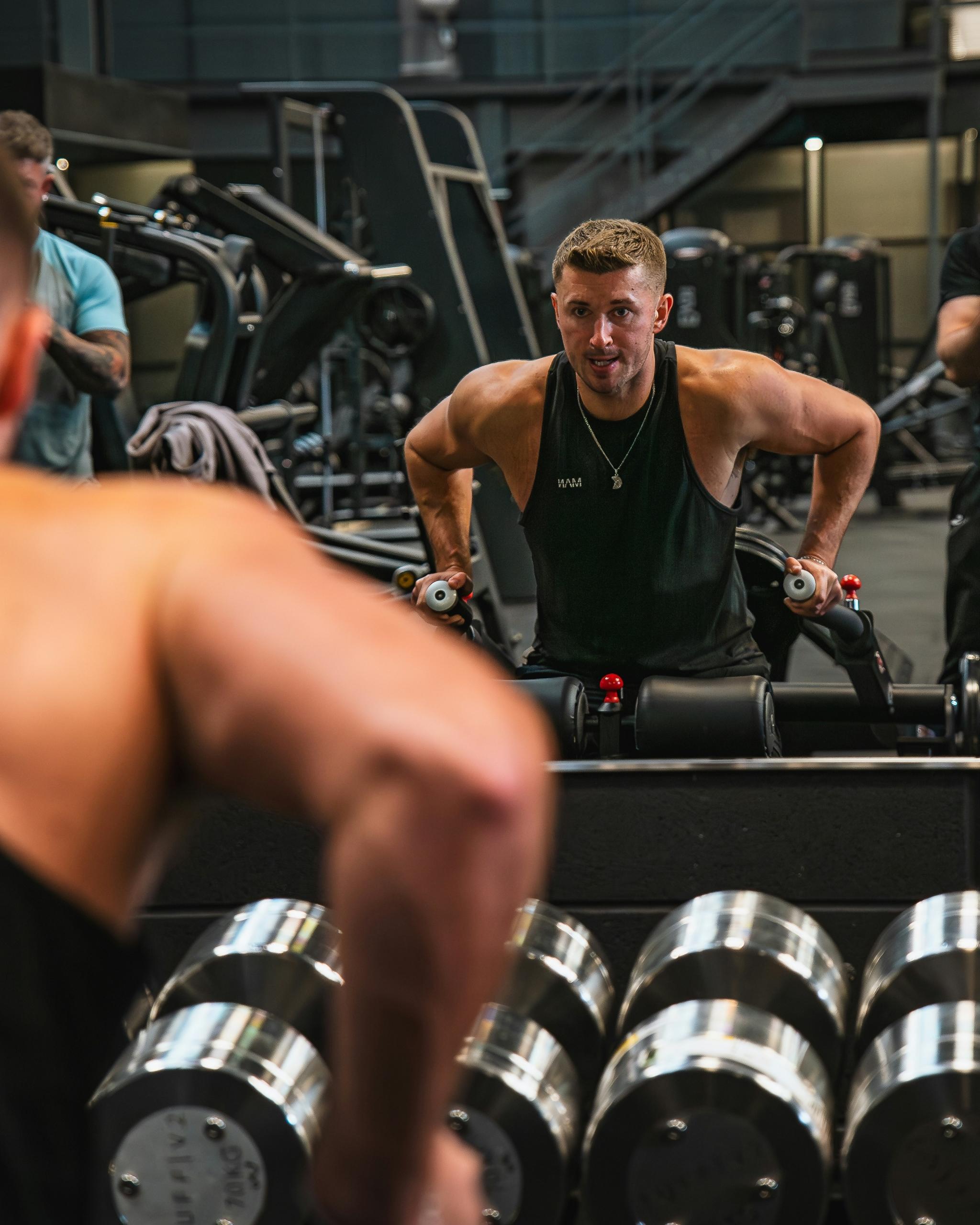 A man is checking his techniques in the gym mirror