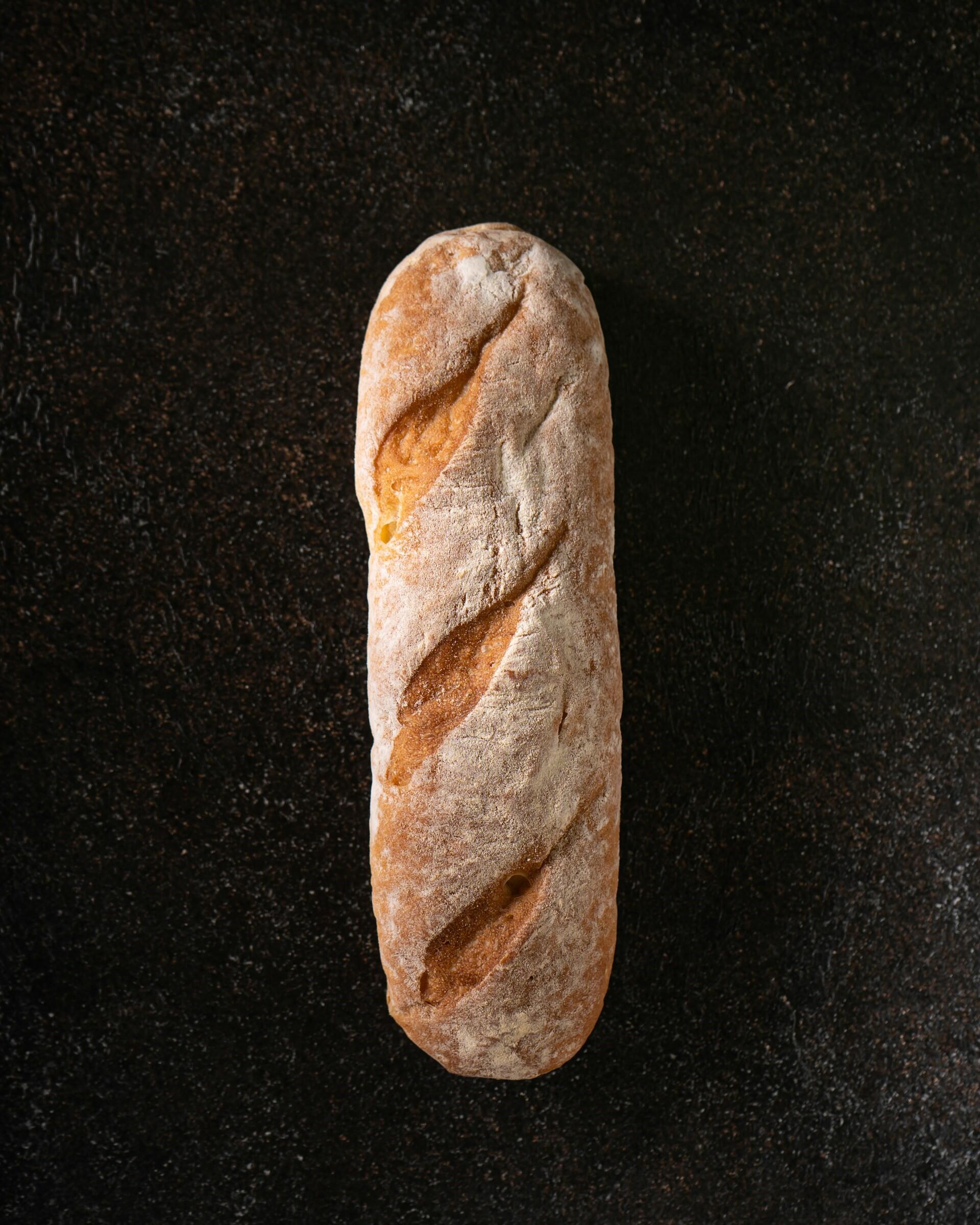 Flour-dusted loaf of bread on a dark surface