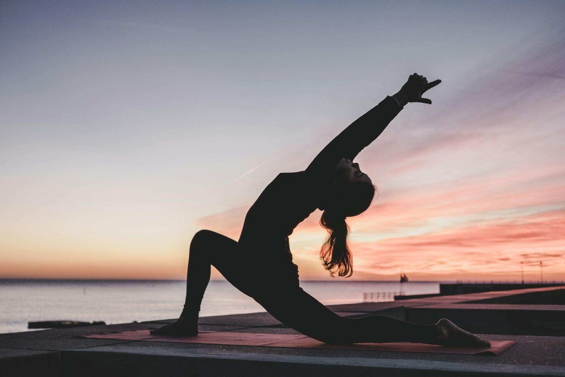 Person practising a yoga pose at sunset, representing yoga poses for beginners and mindful movement