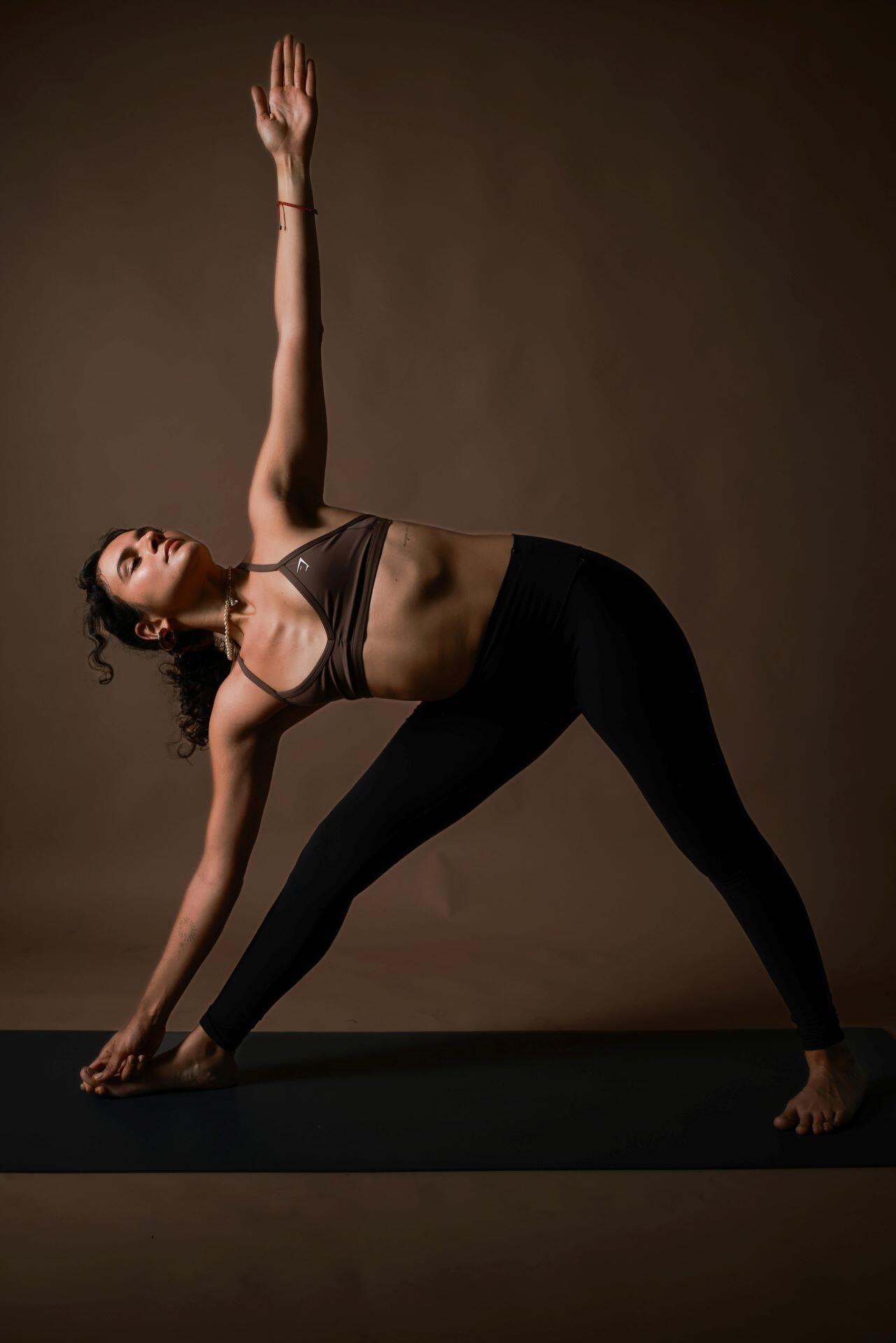 Woman performing Triangle Pose with one hand reaching toward the foot and the other arm extended upward