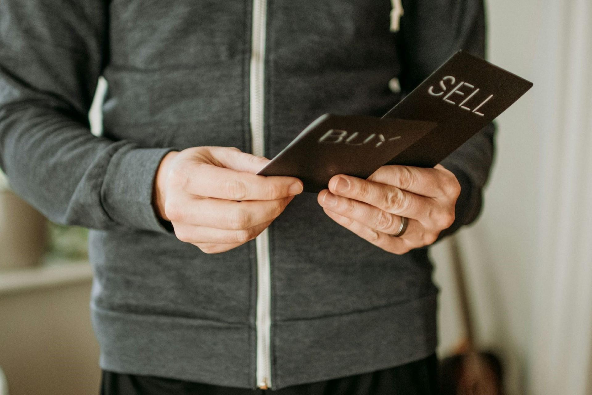 A man with cards labelled buy and sell.