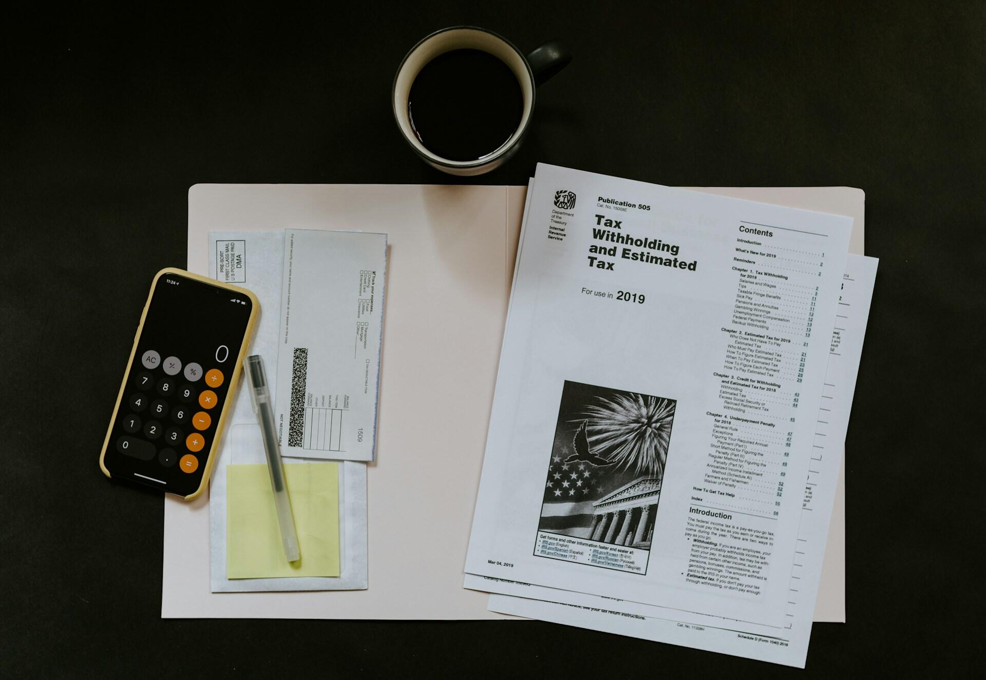 Accounting documents next to stationery and a calculator.