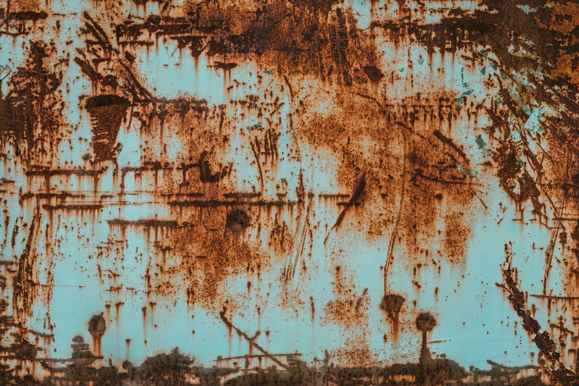 Rust patches and streaks on a blue-painted metal surface