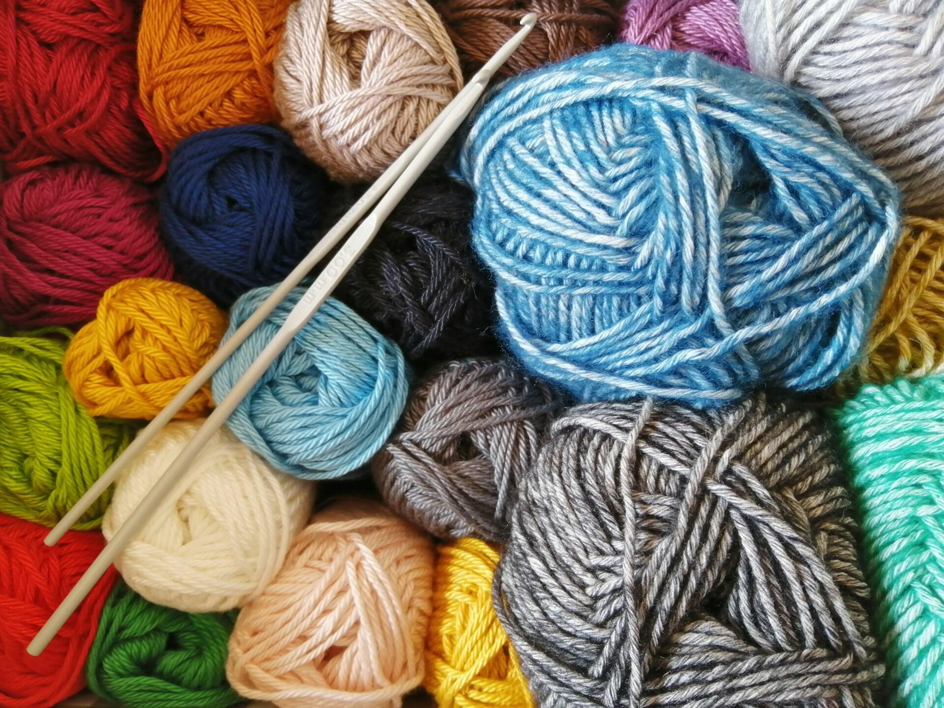Colourful balls of yarn with crochet hooks resting on top