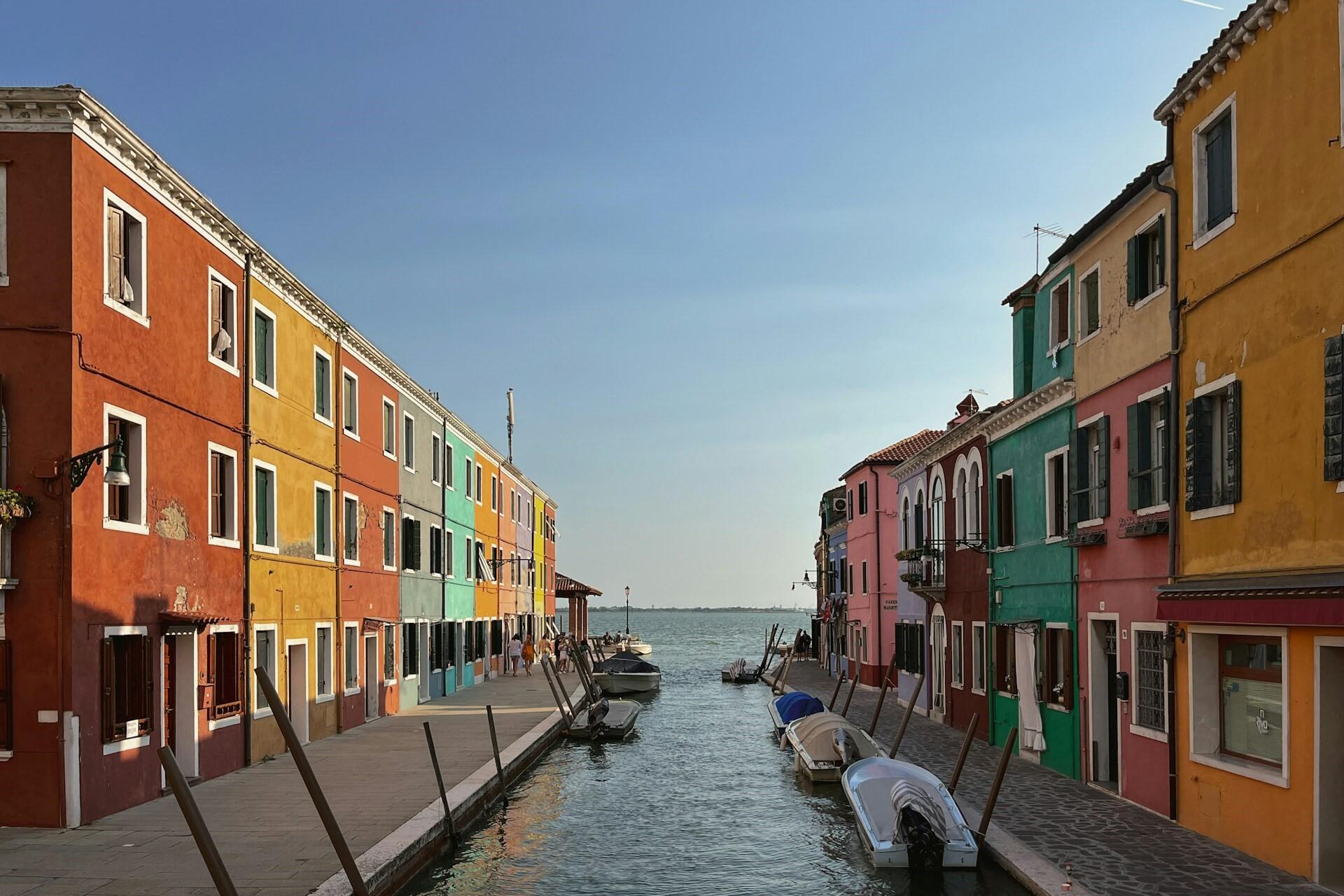Colourful houses lining a canal in Burano with boats and calm water