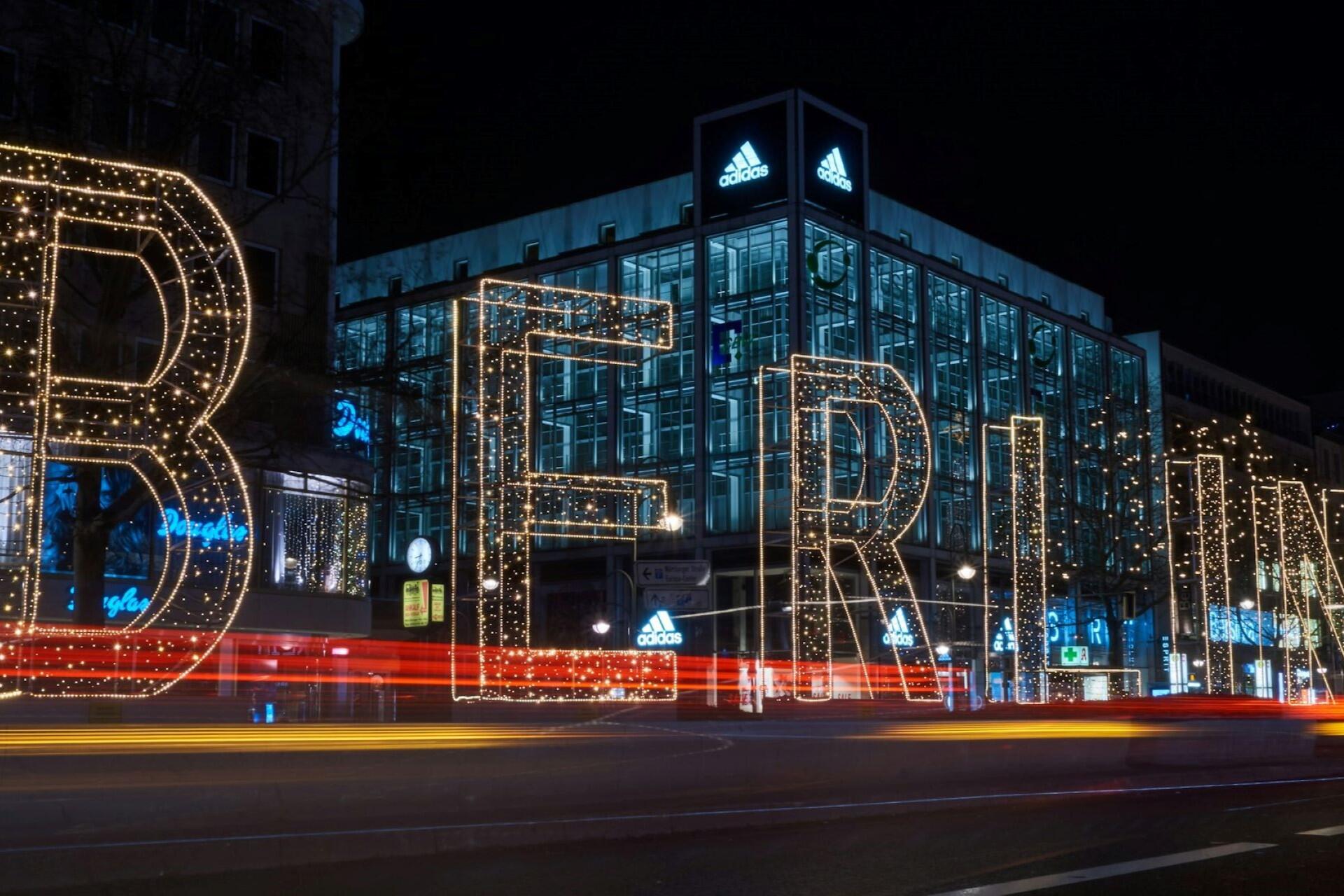 Berlin street at night with illuminated letters and traffic light trails