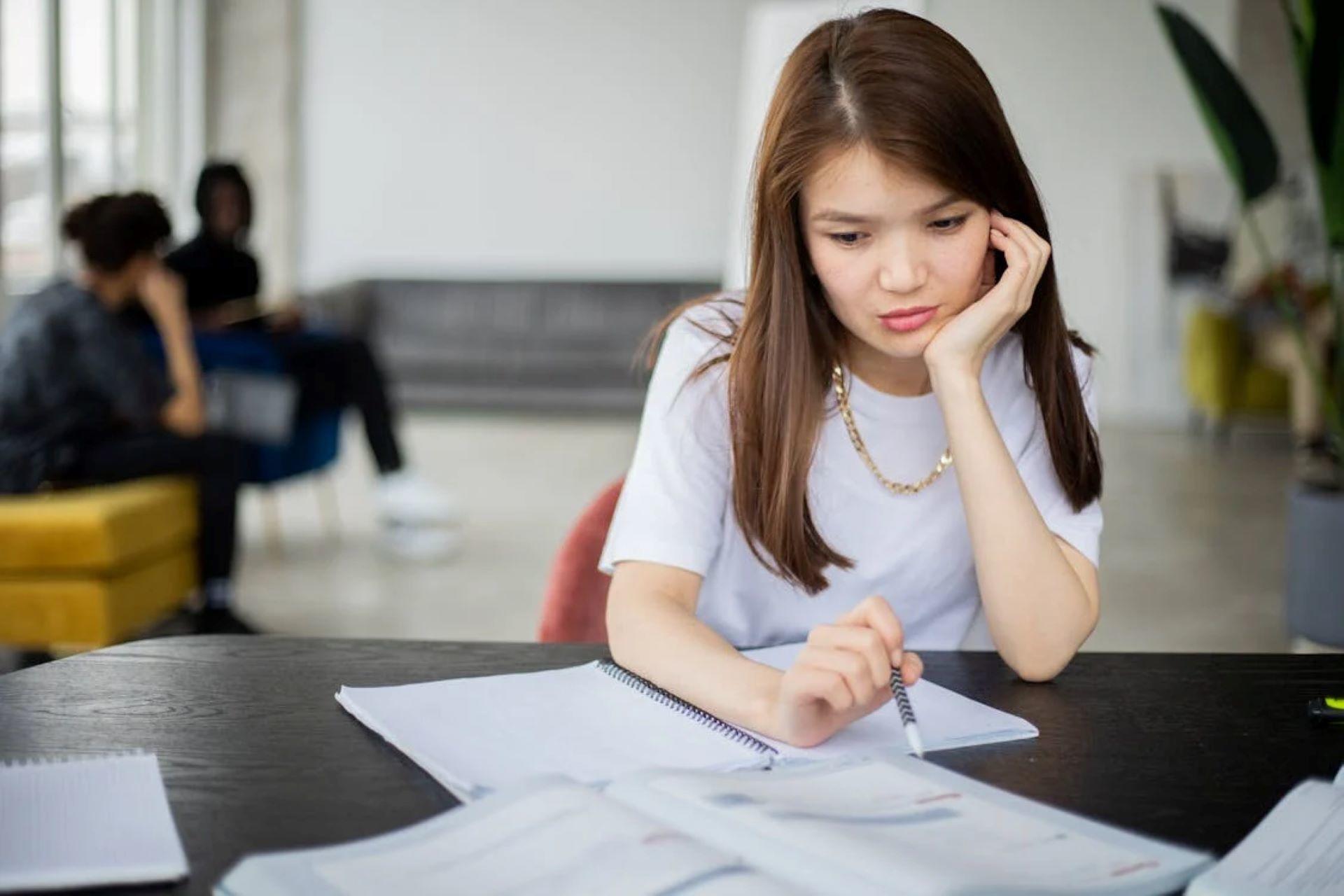 A woman studying Irish with textbook and papers, deep in thought