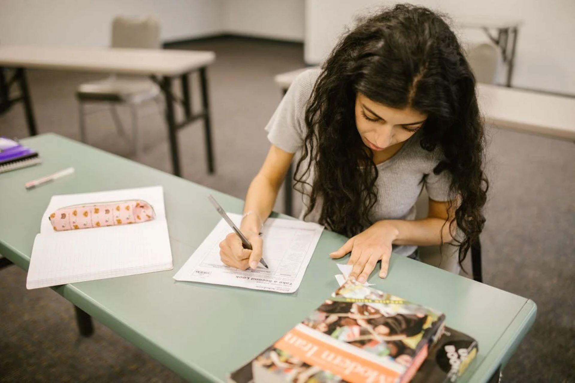 Student studying Irish language materials in a library with books and notes.