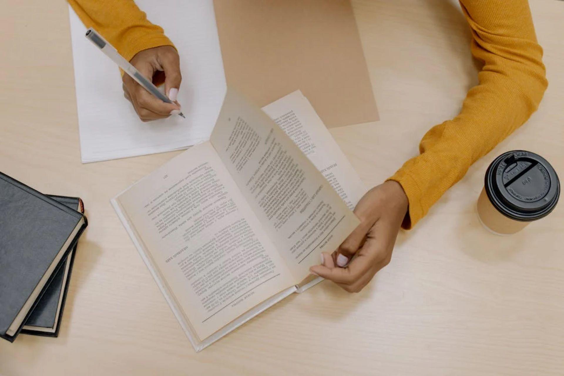 tudent studying at a desk with book, notes, and coffee