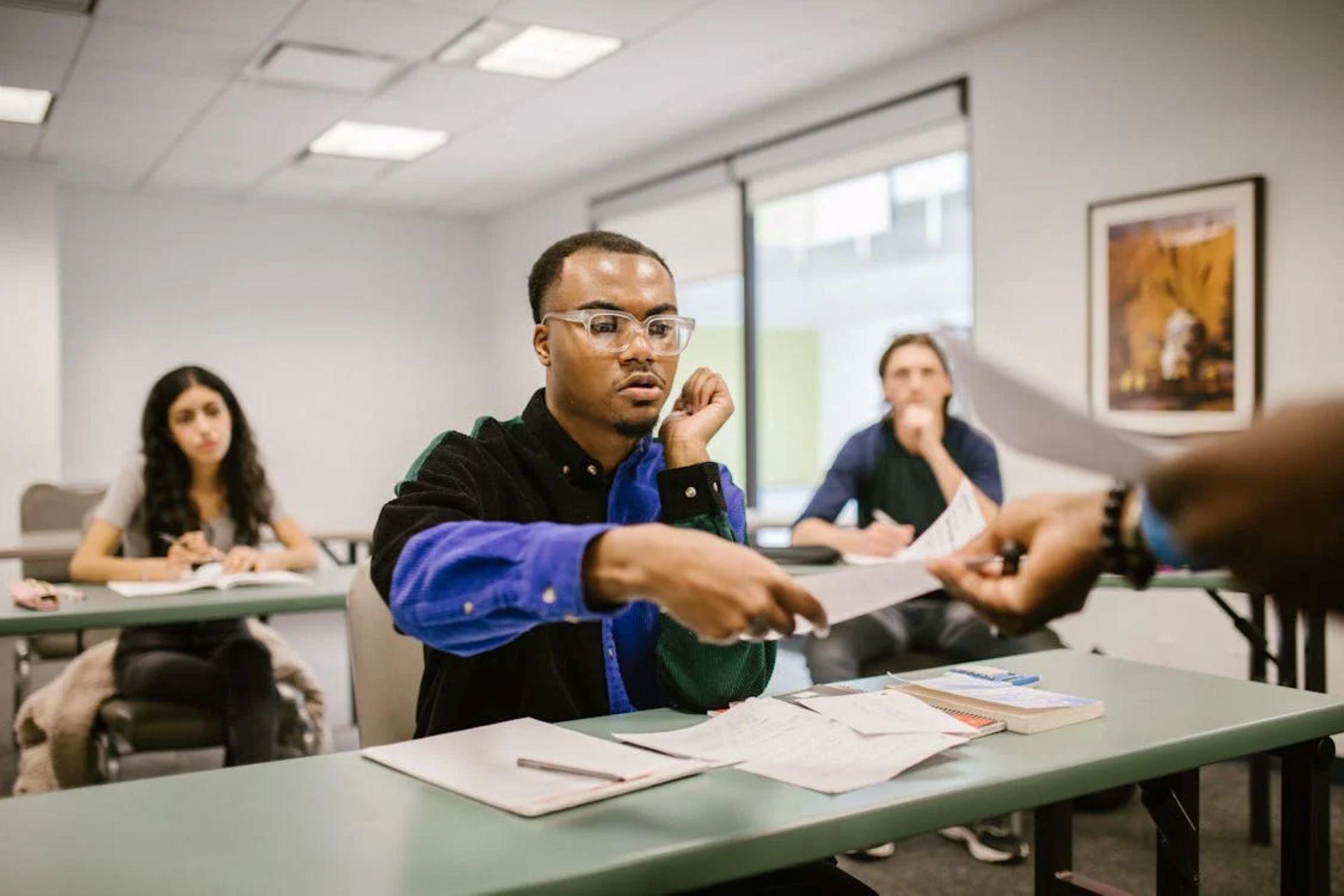 Students receiving exam paper in a classroom