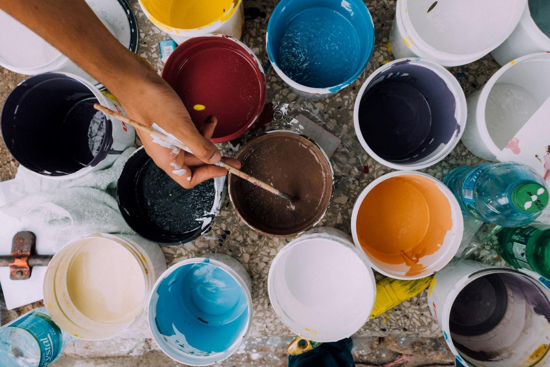 A series of paint pots and somebody using them to paint.
