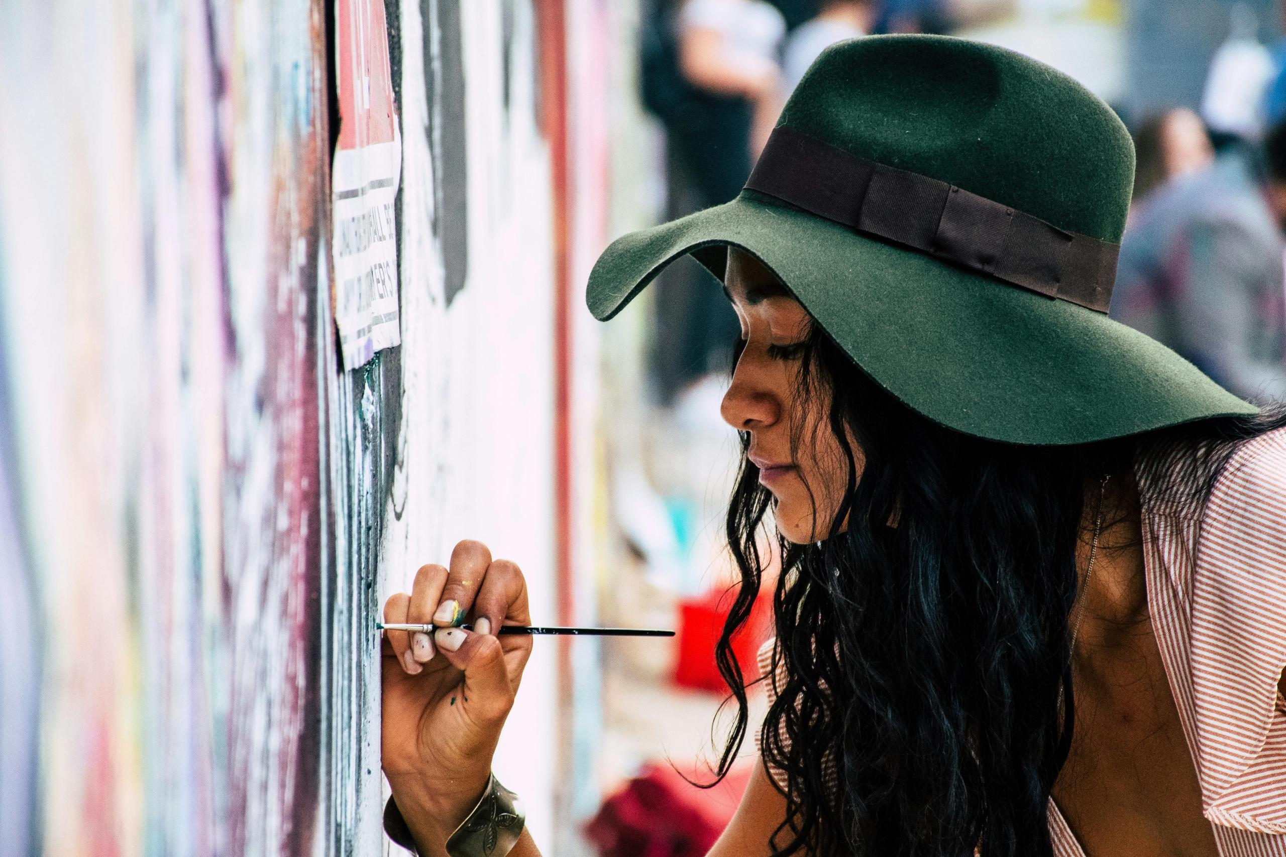 An artist using her oil painting techniques to craft an appealing image onto a city wall.