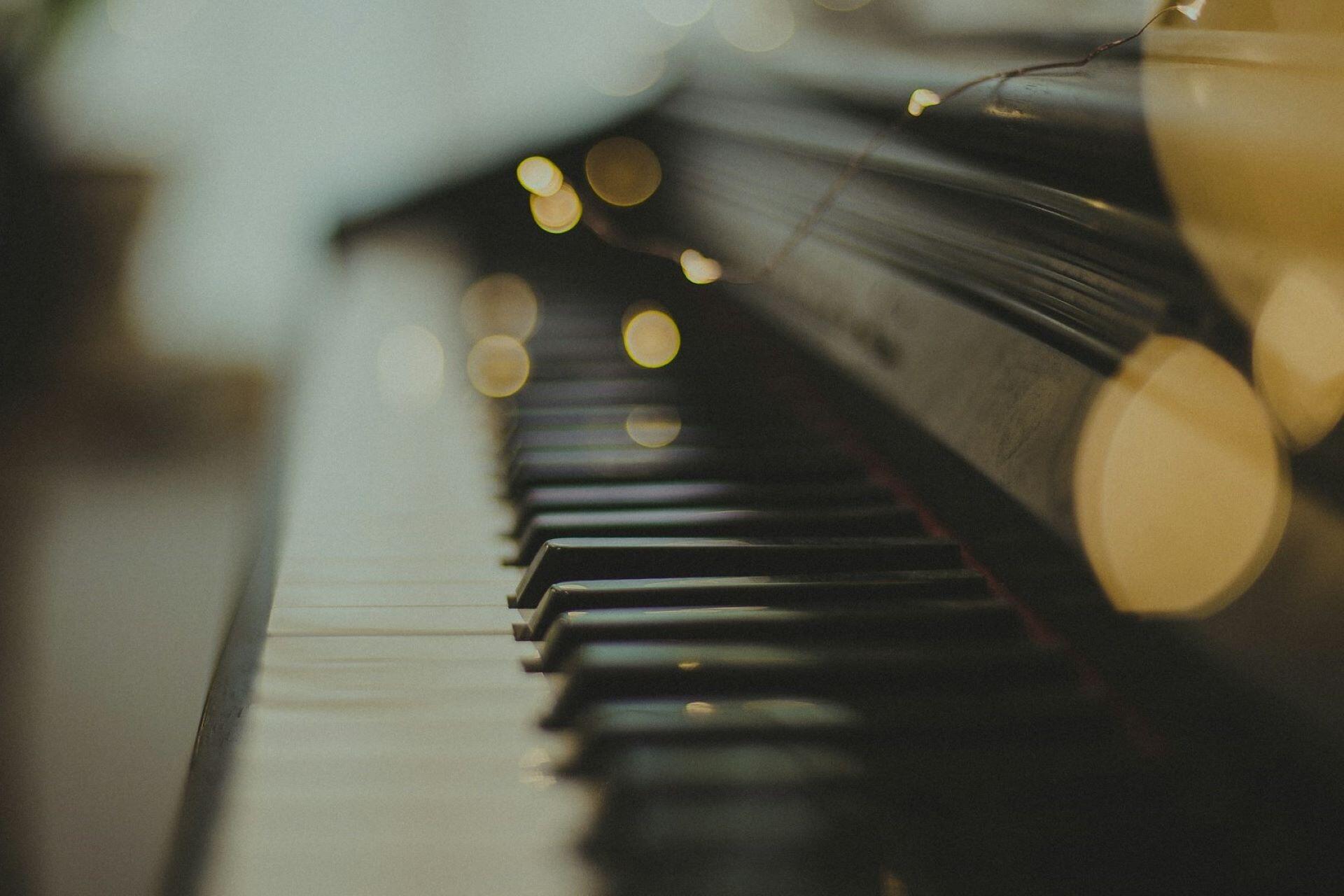 Close-up of piano keys with warm lights in the background