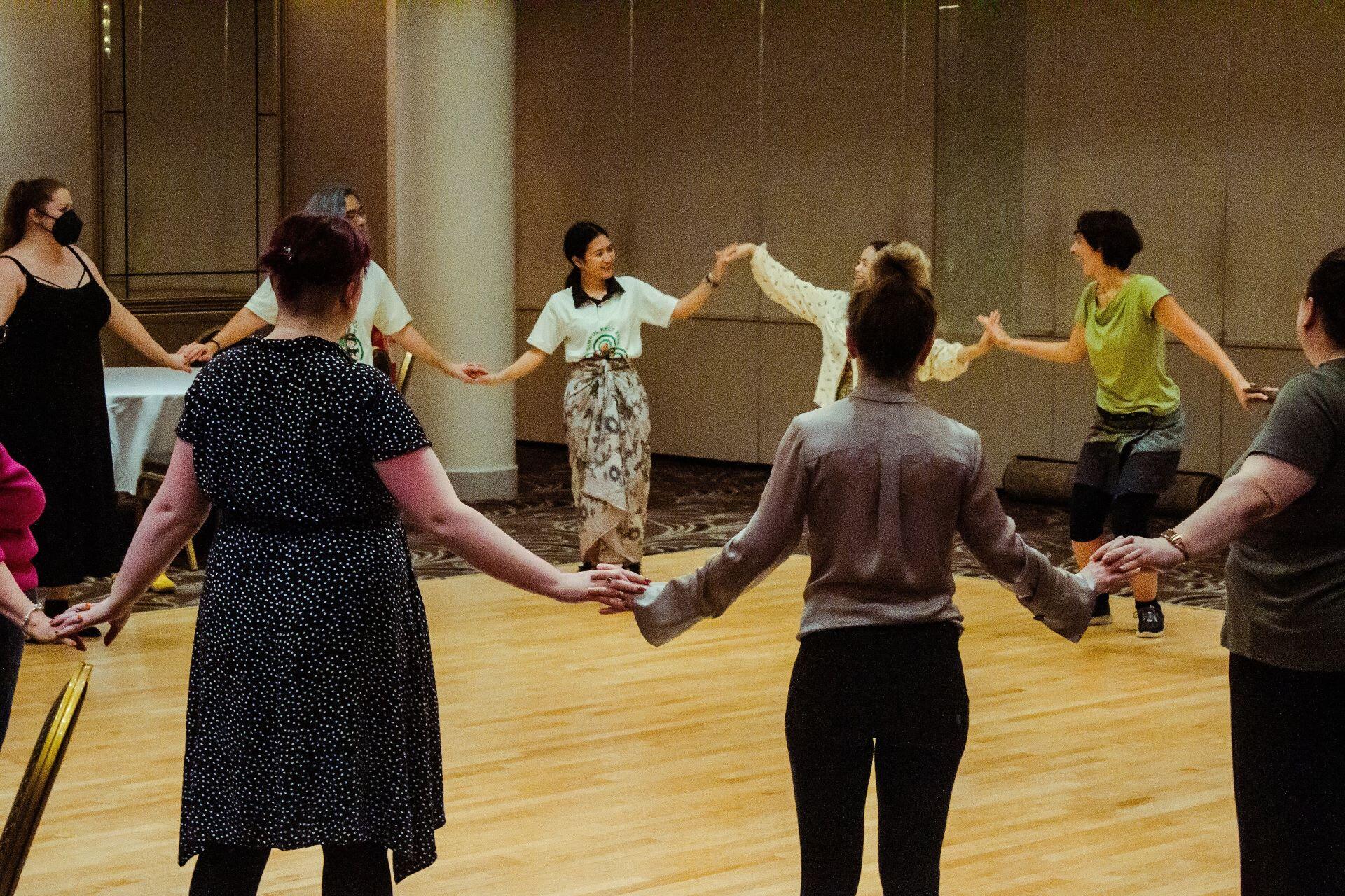 Adults holding hands in a circle during a dance workshop