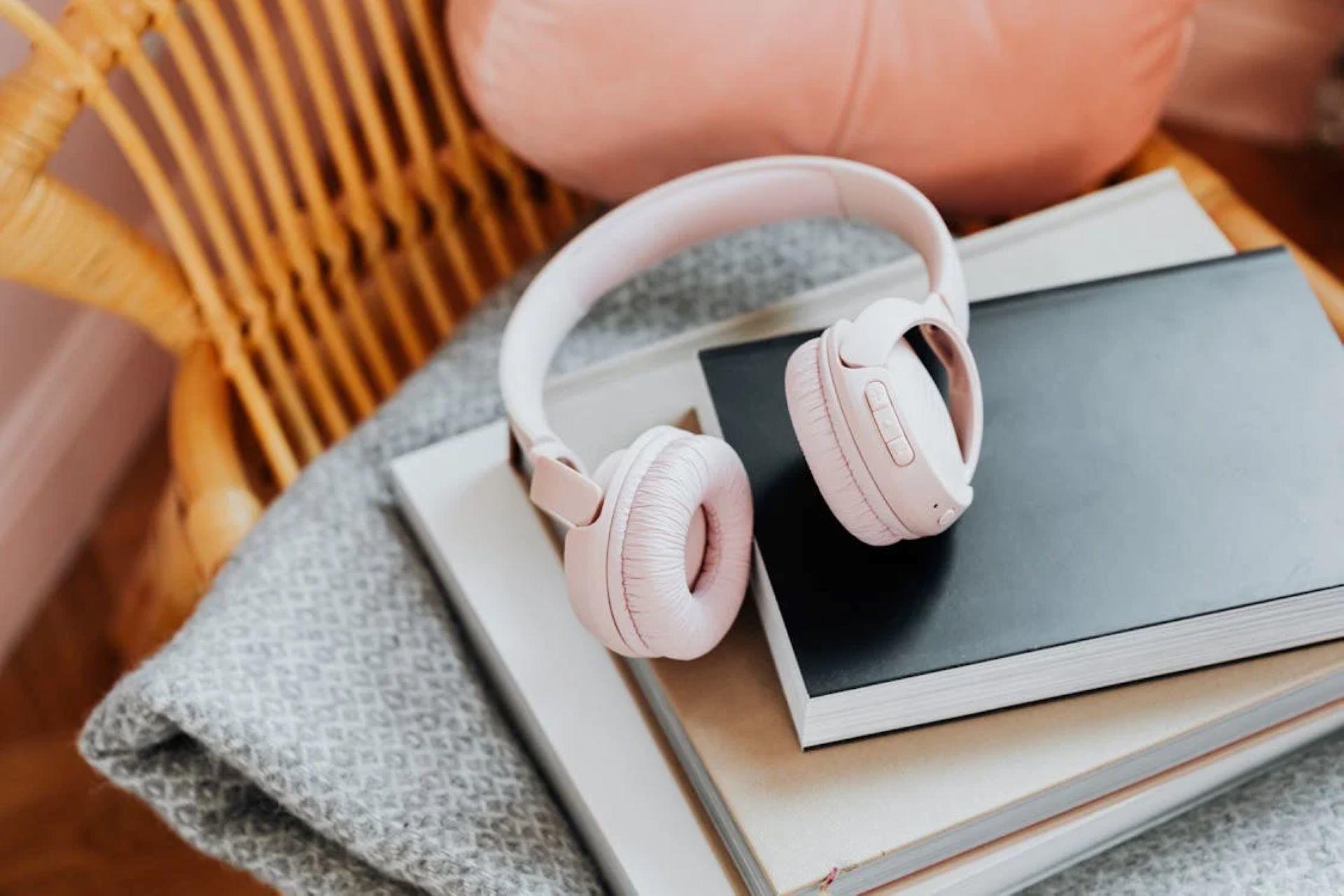 Pink wireless headphones on a stack of books