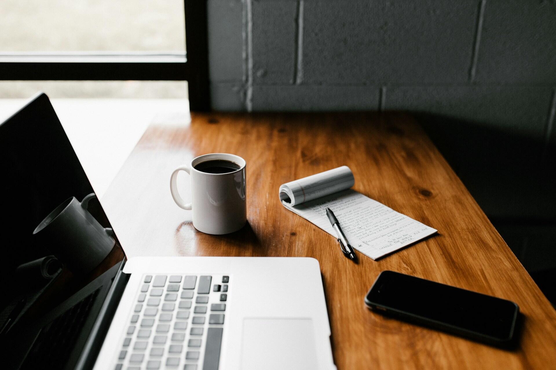 A laptop with notes and a coffee.