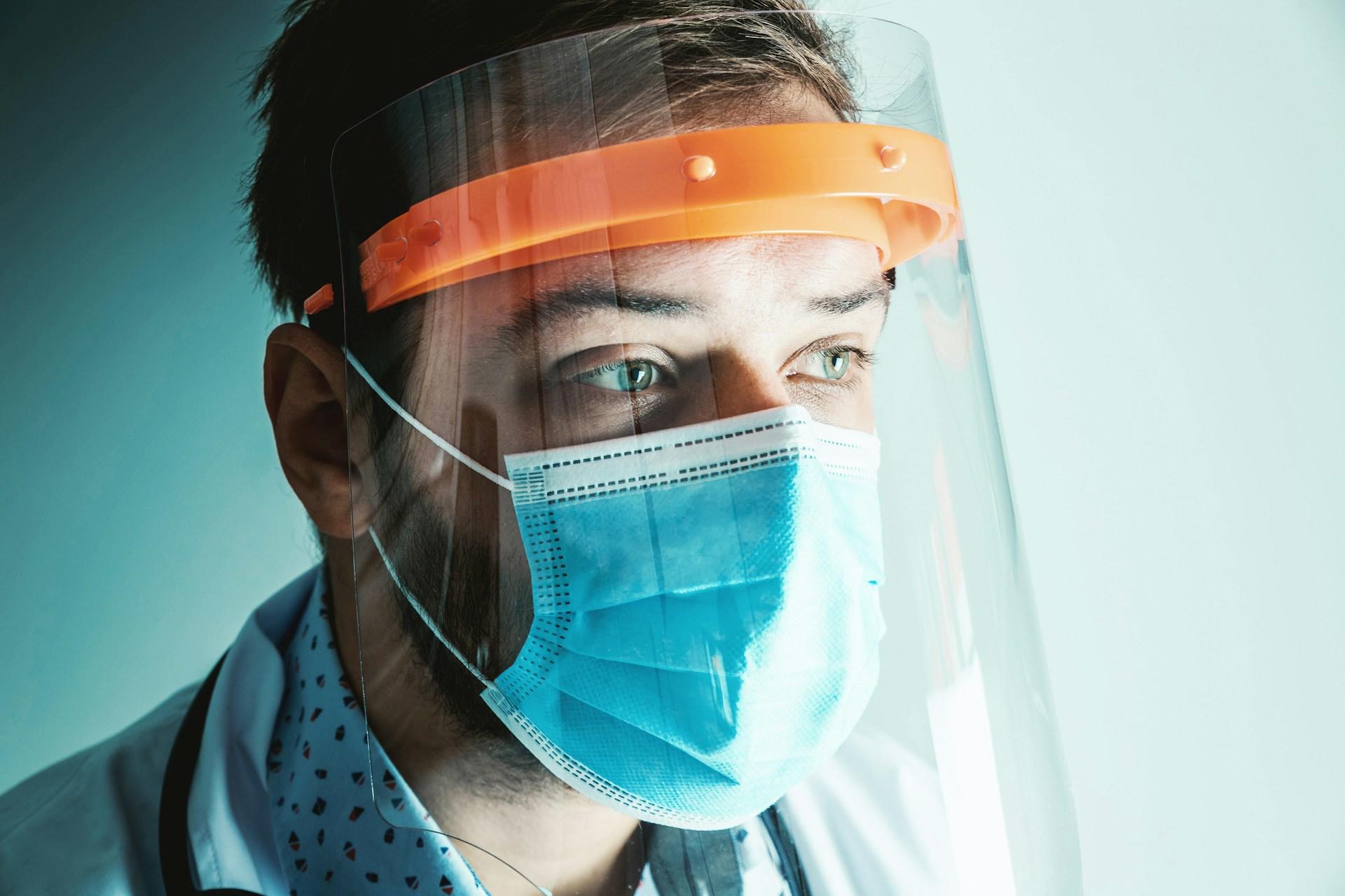 A doctor with a face mask and face shield.