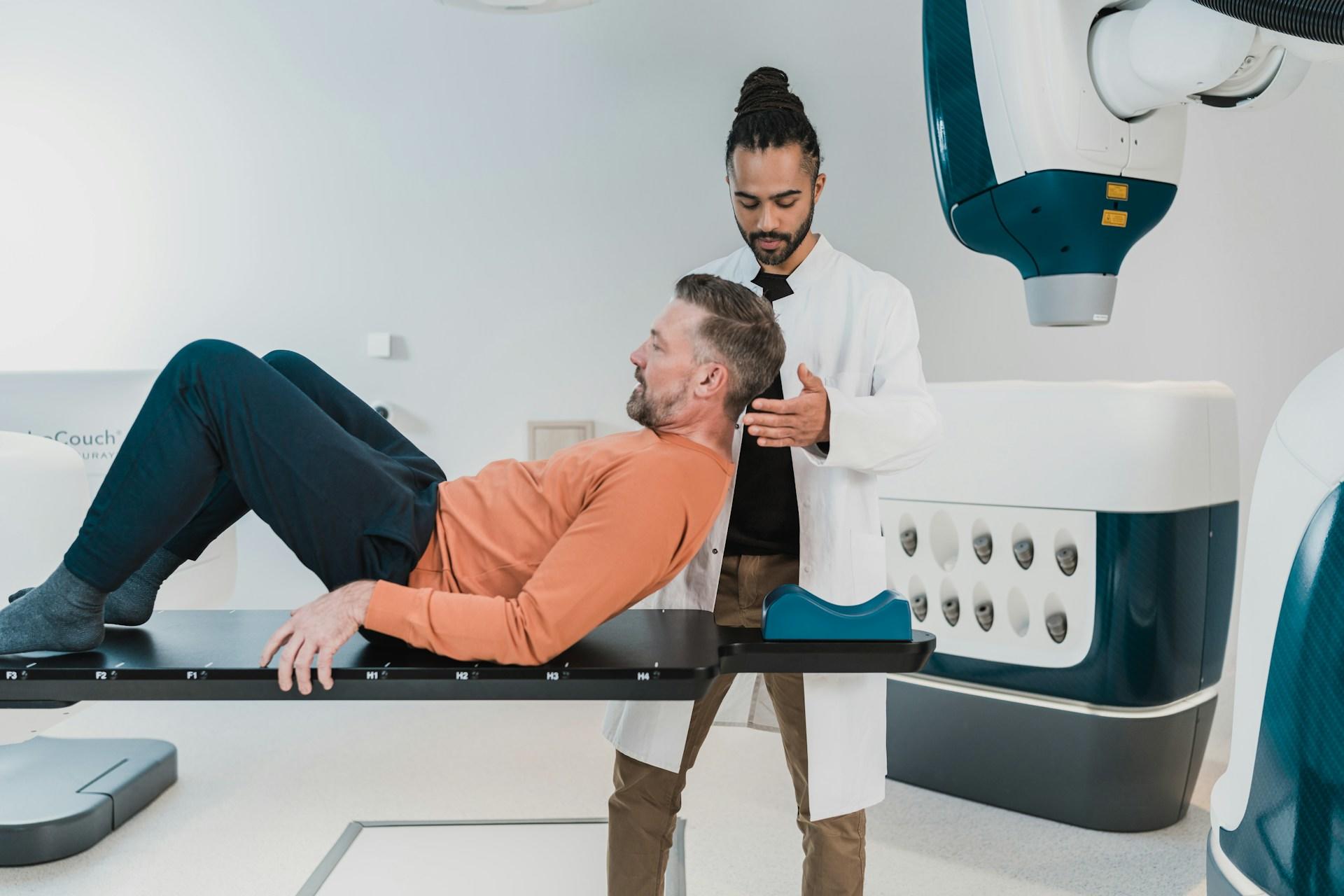 A doctor helping a patient onto a scanner.