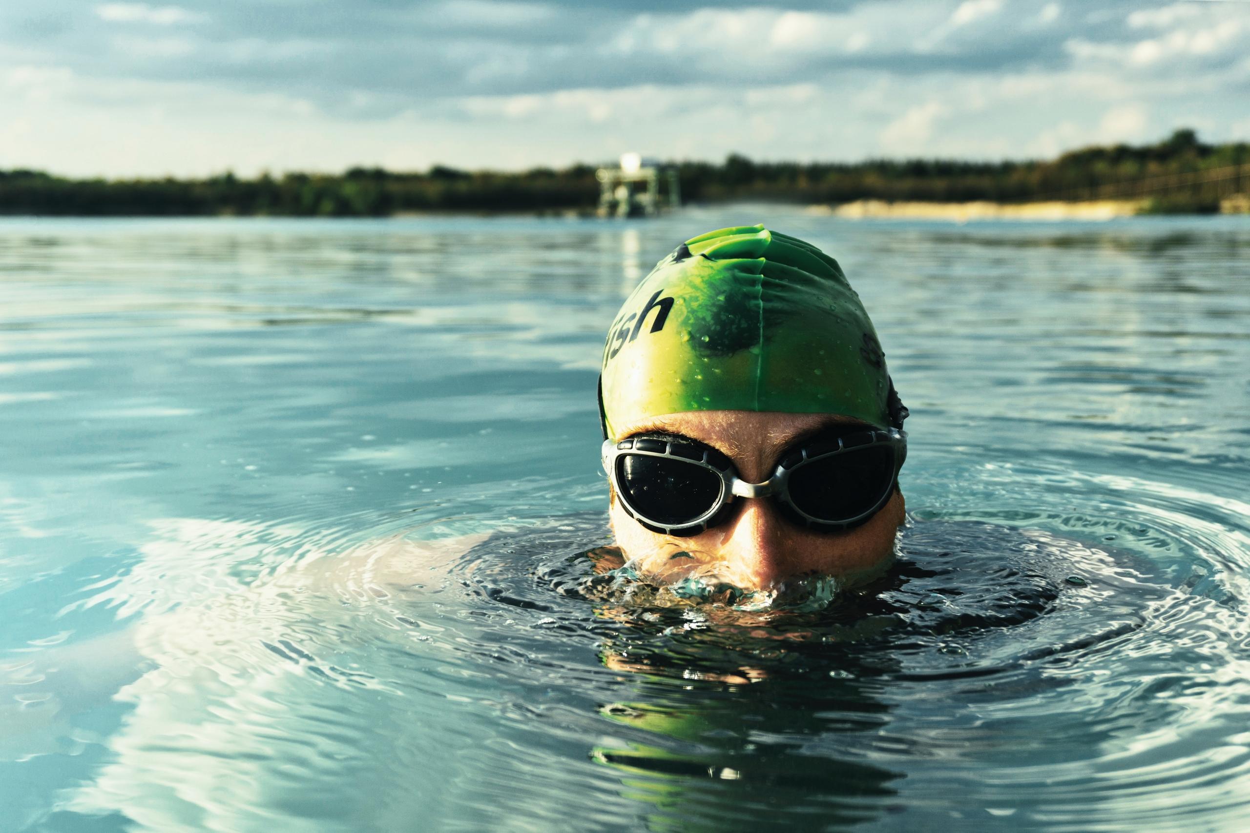 A serene sight of a lone swimmer gliding gracefully through the calm, azure sea, enjoying a moment of peaceful solitude amidst nature's beauty