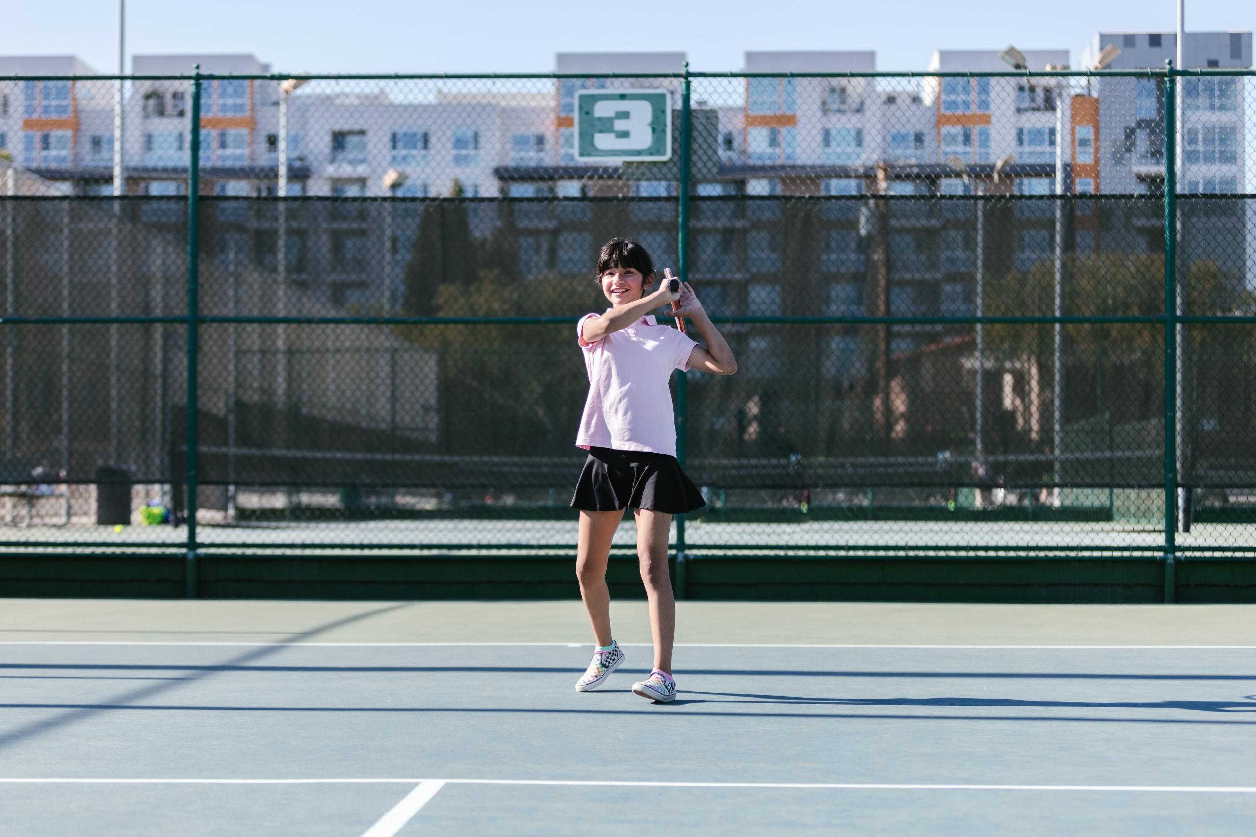 A young boy hitting his tennis racket at a court