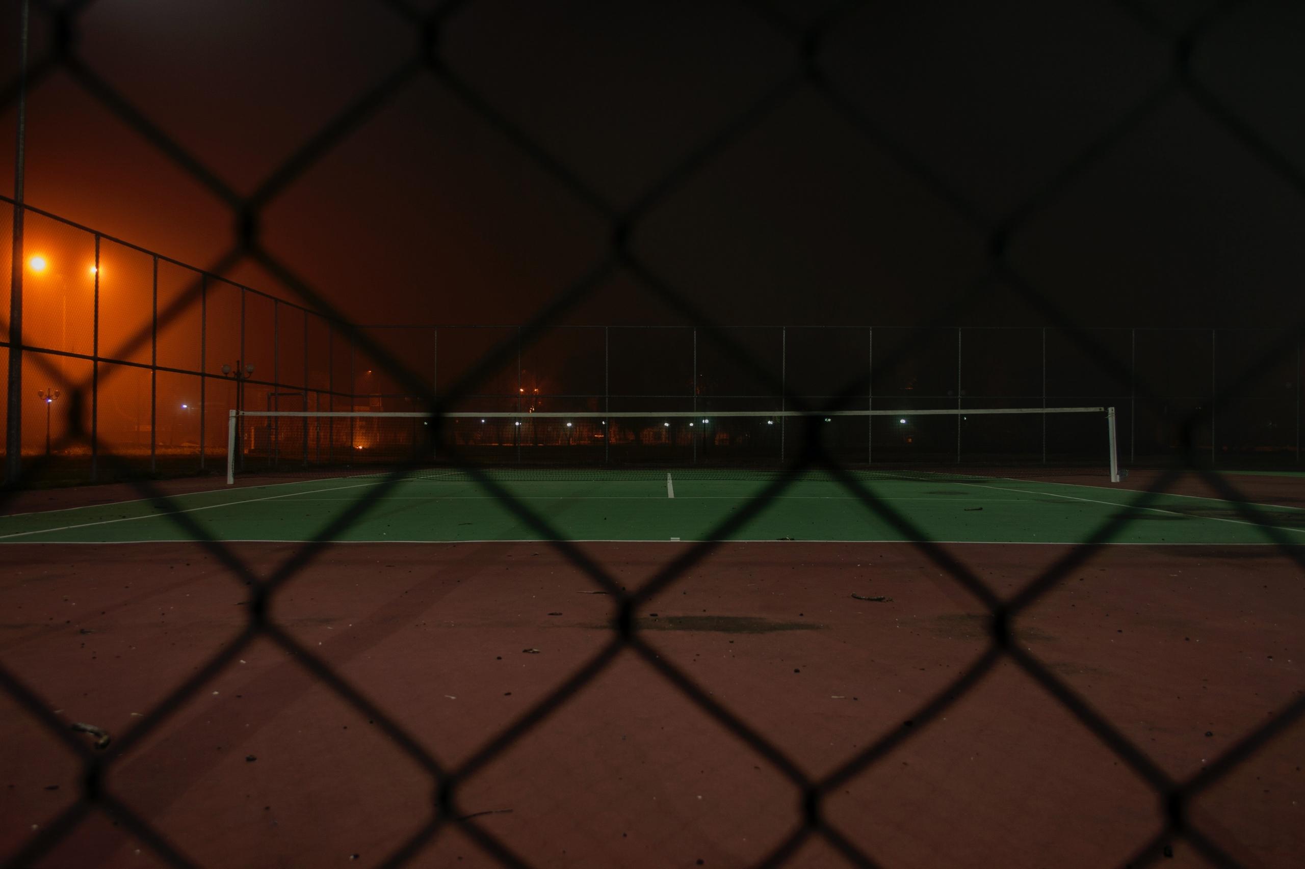 An empty tennis court at night time