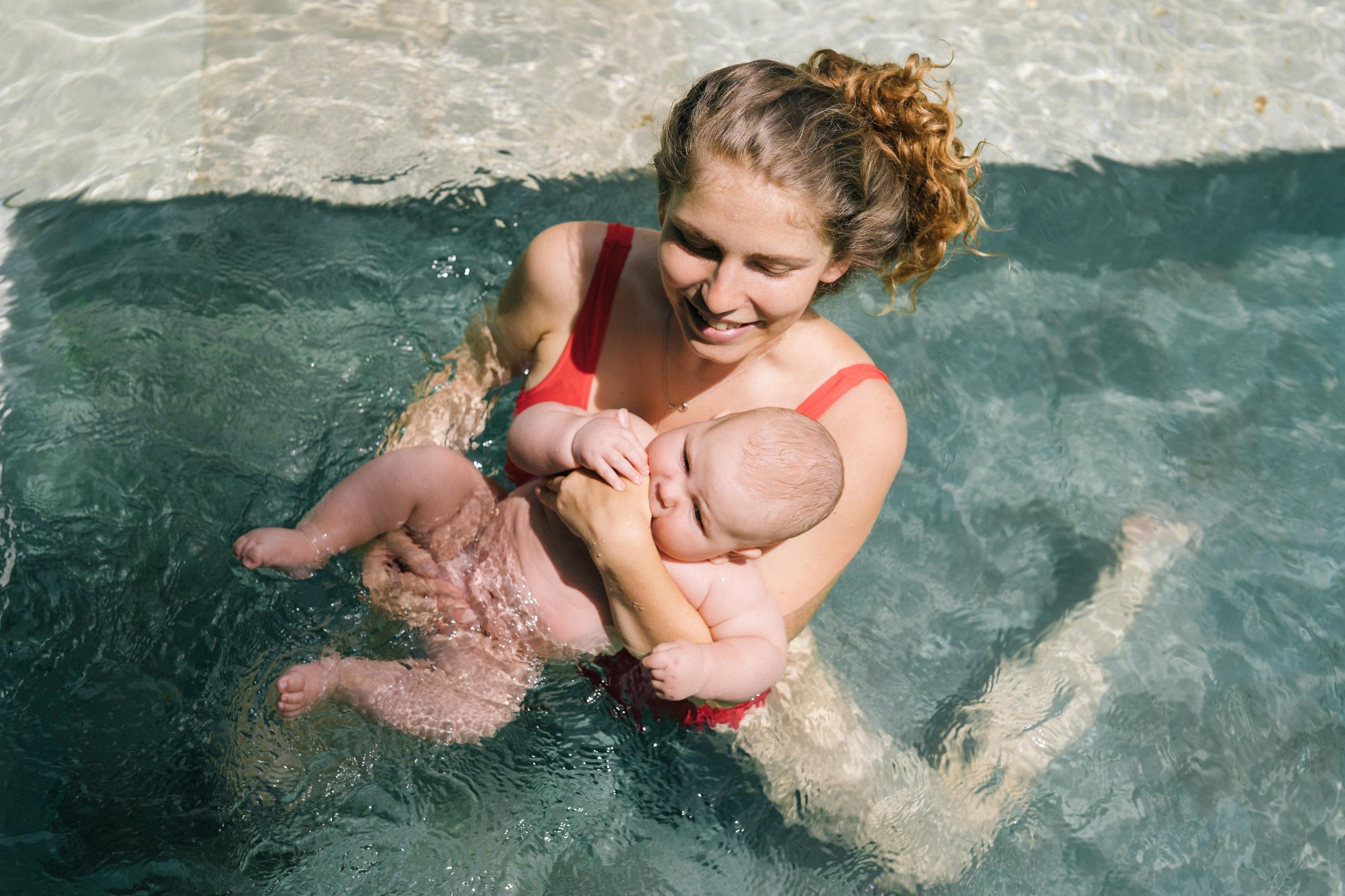 In a picturesque setting, a radiant expectant mother embraces the water, cherishing the buoyancy and relief it brings while swimming during pregnancy.