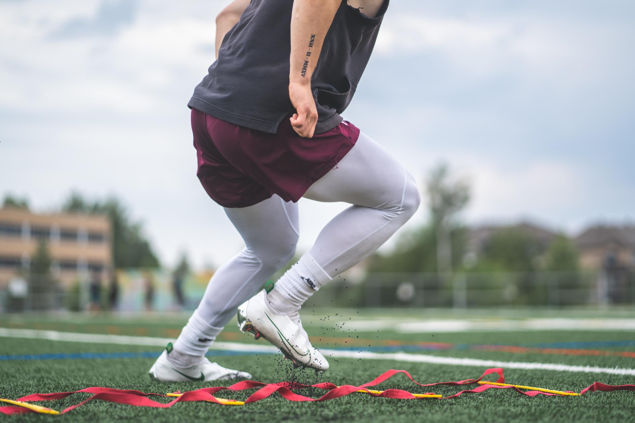 Focused athlete training on a football pitch.
