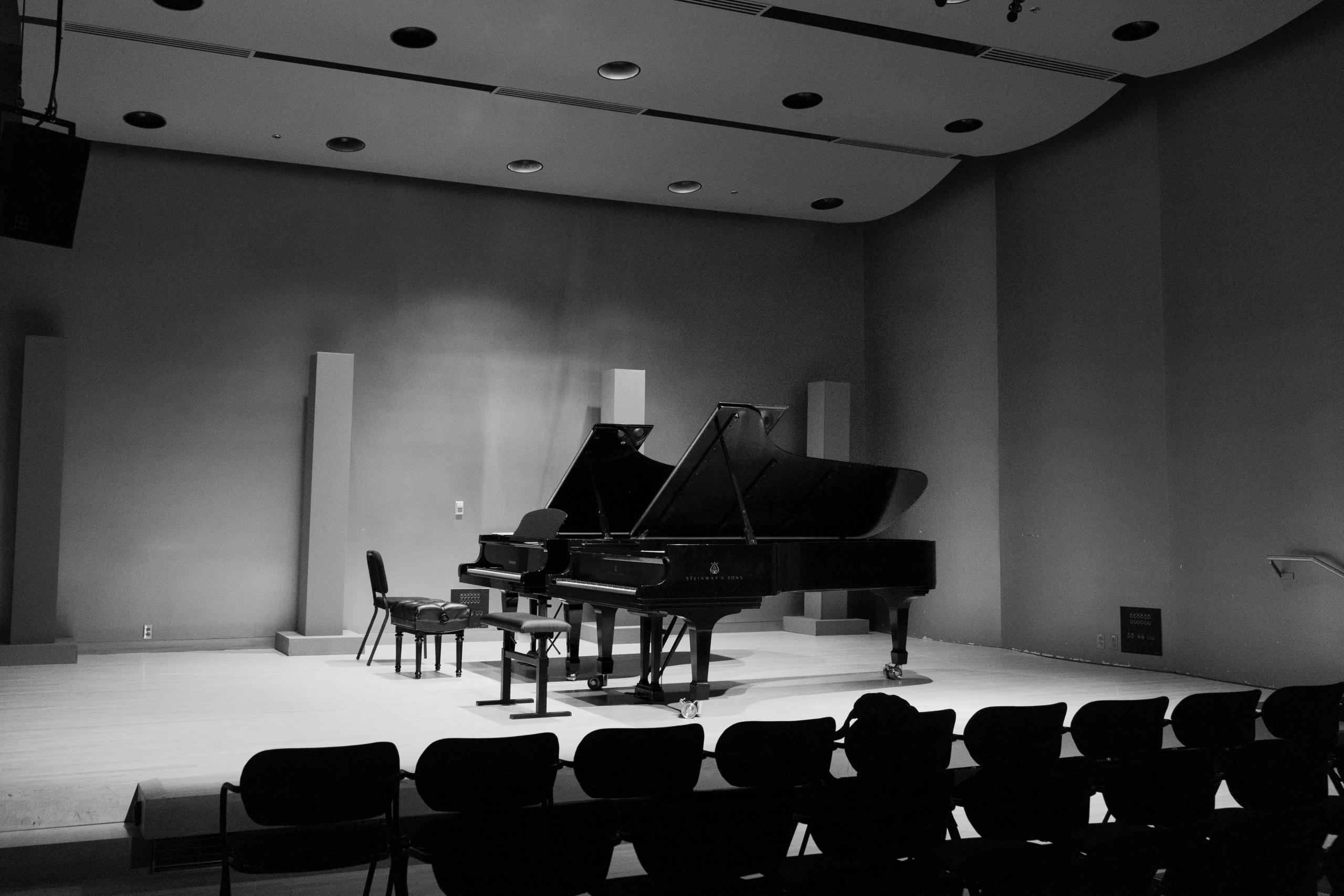 A piano in front of rows of seats.