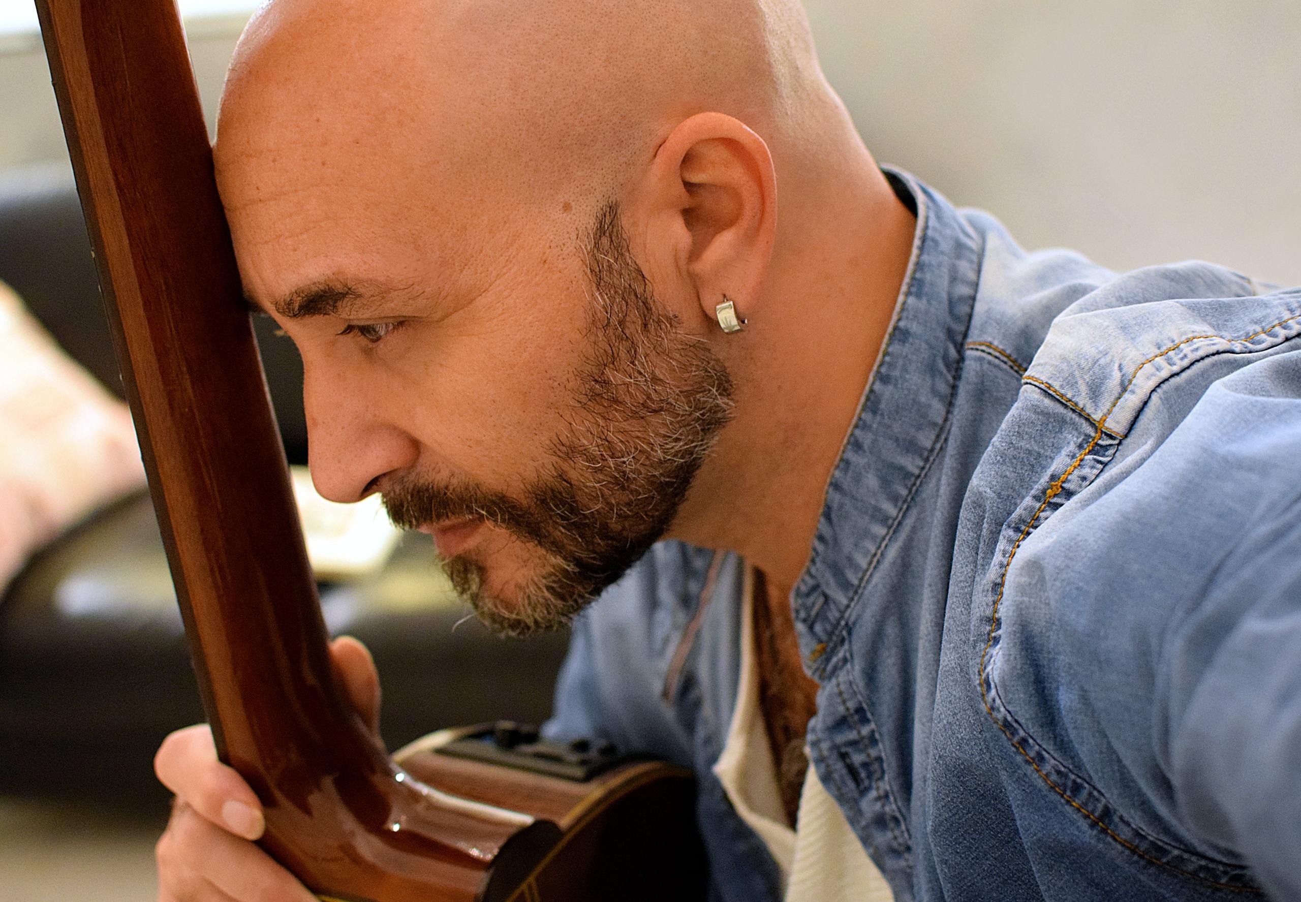 A man holding the neck of his guitar.