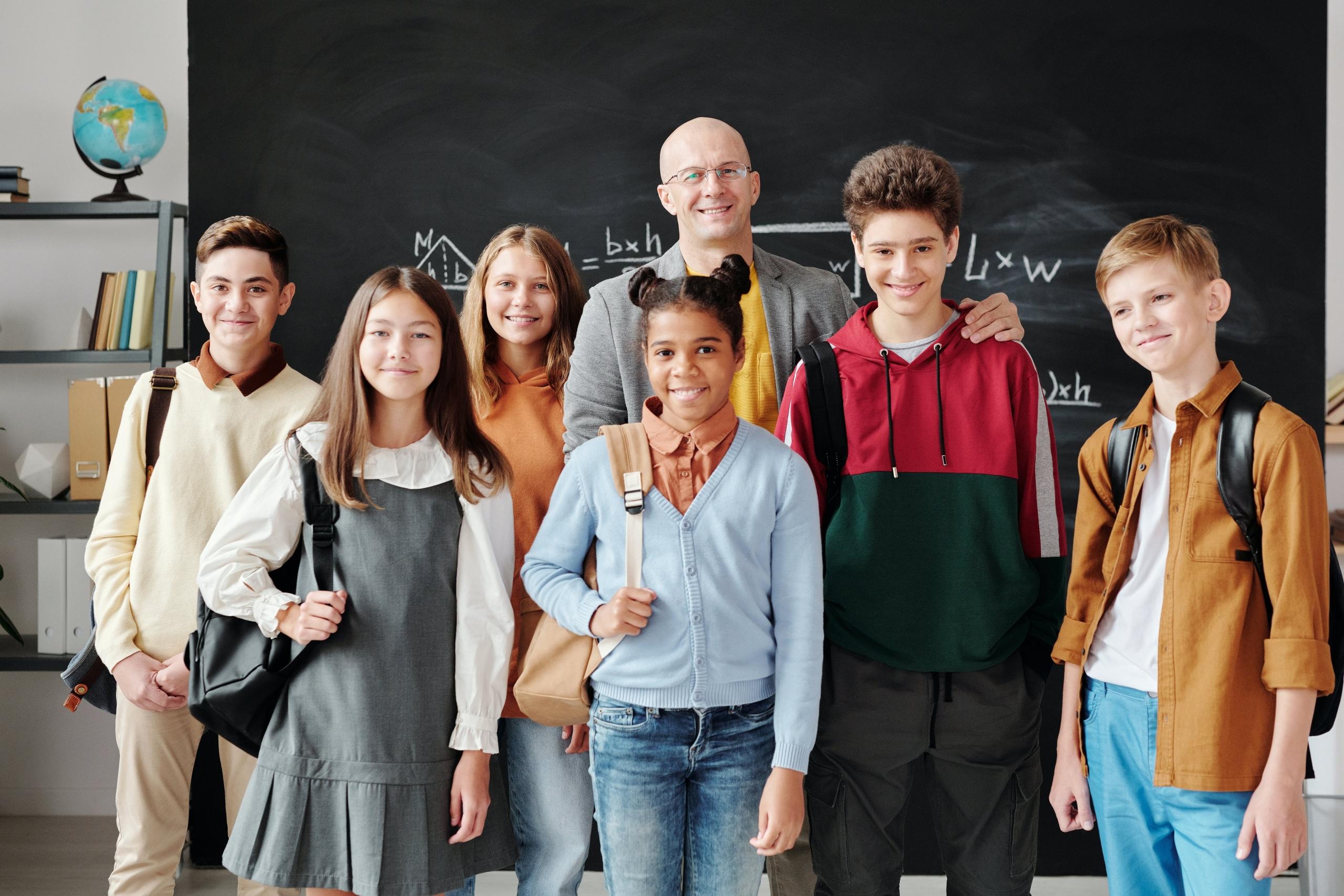 A proud teacher standing alongside his students in class.