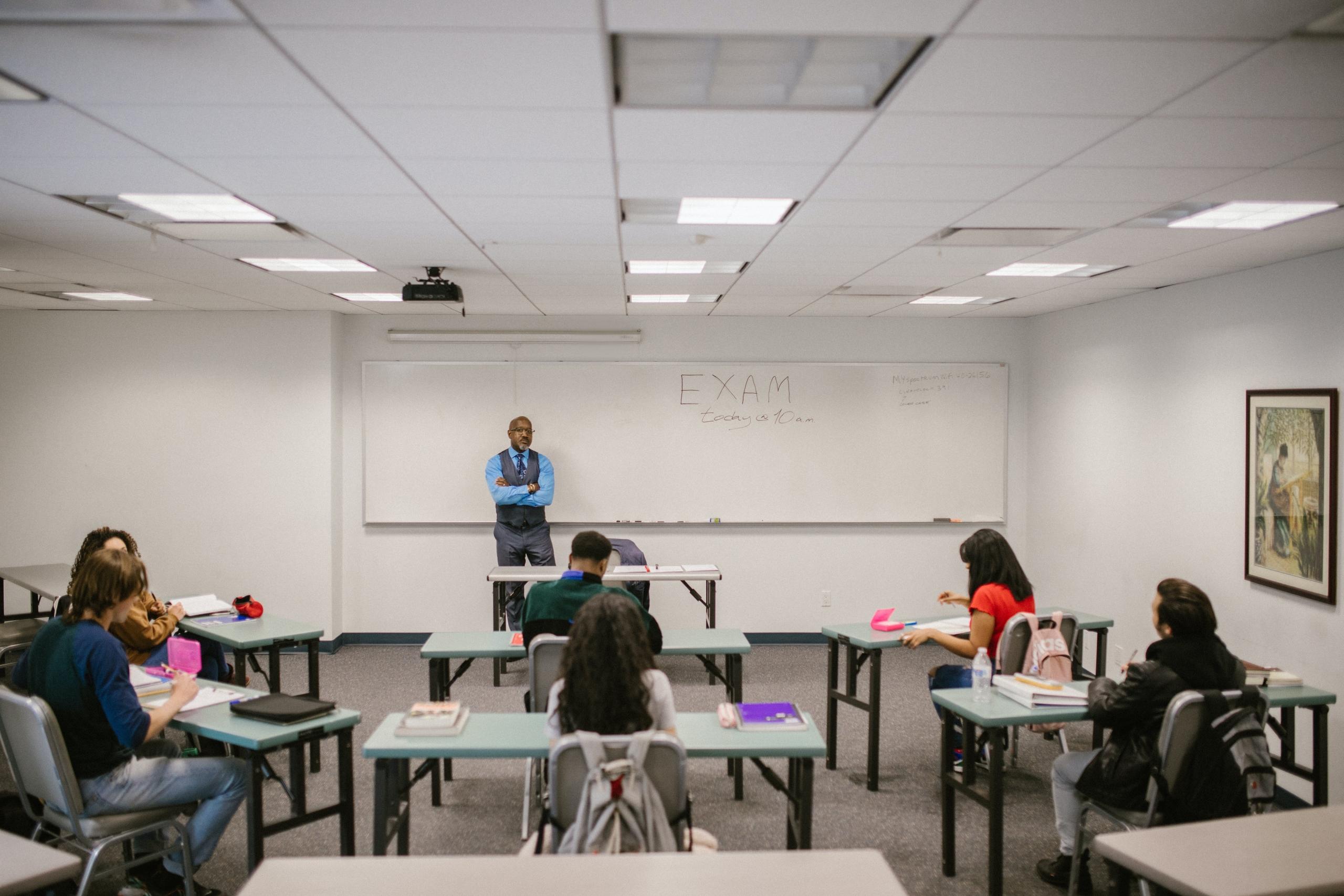 A teacher standing in front of his whiteboard in class.