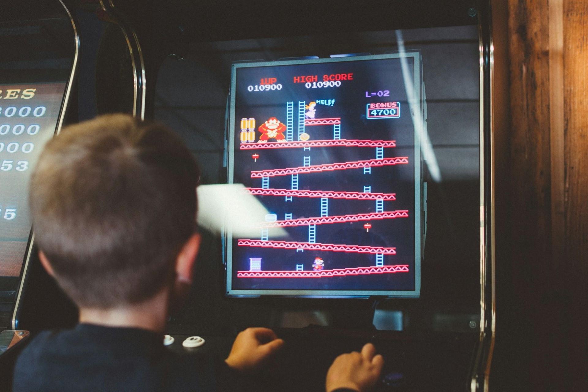 A boy playing a Donkey Kong arcade cabinet.