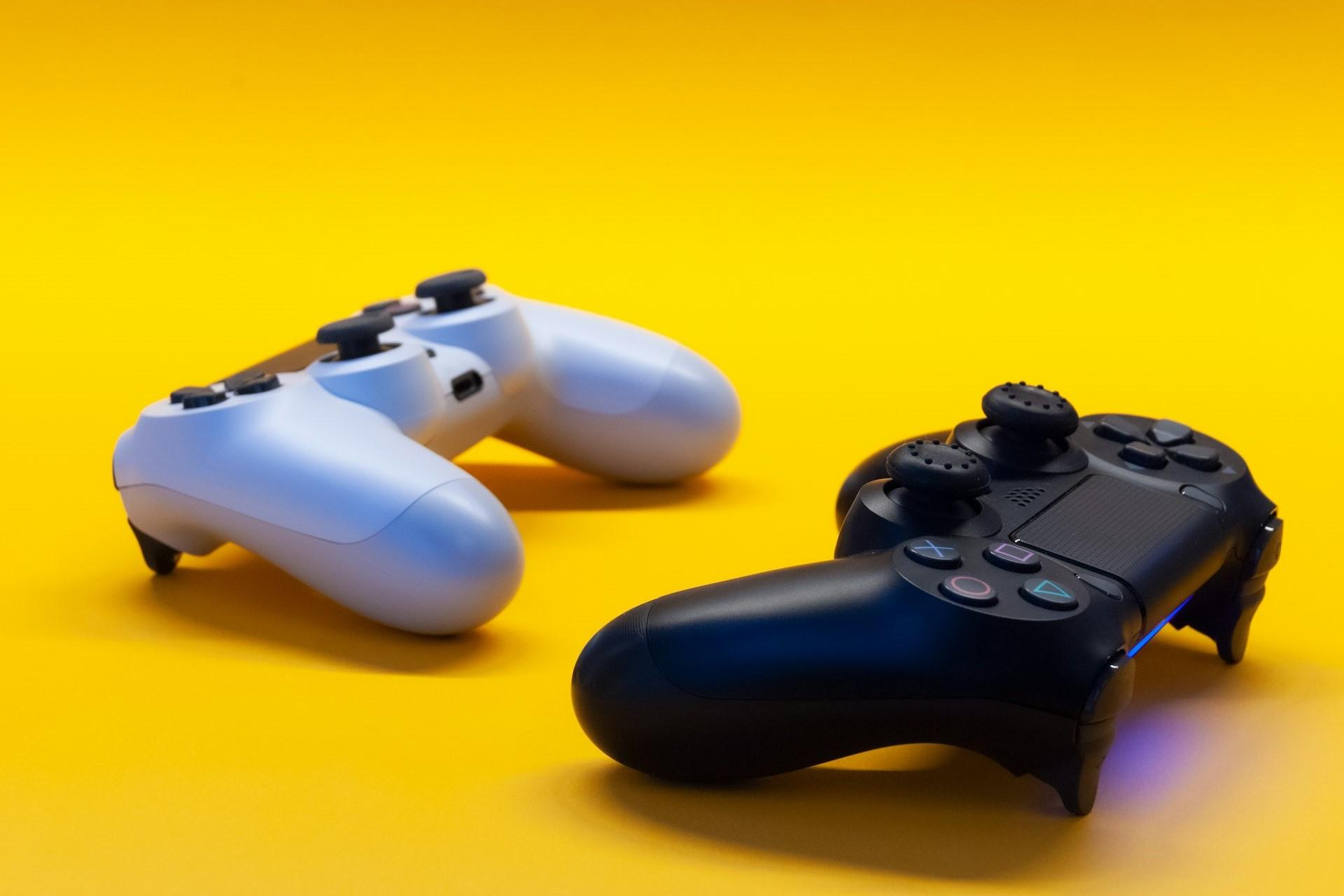 Two PS4 controllers lying on a yellow background.