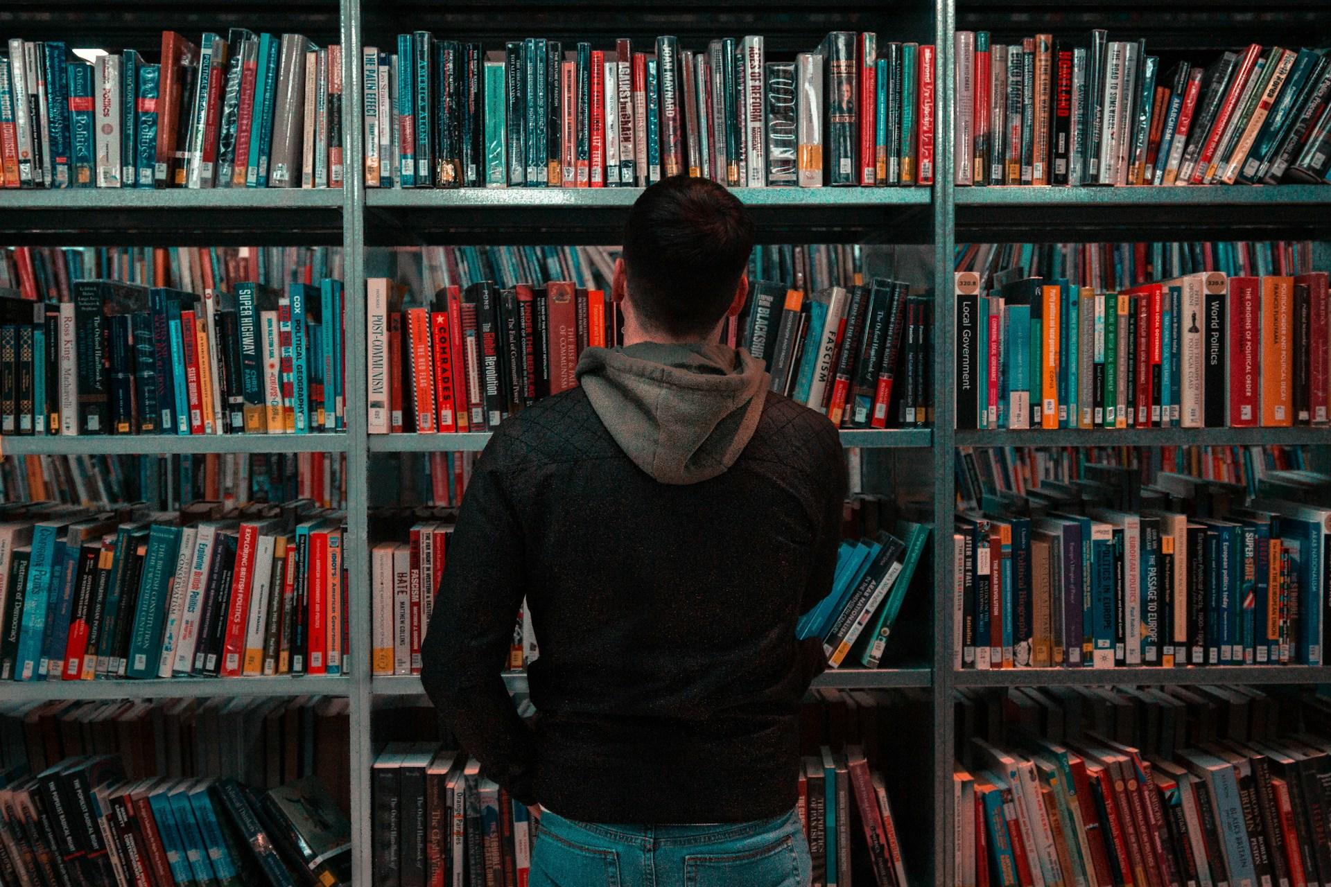 A person looking at a bookshelf in a library.