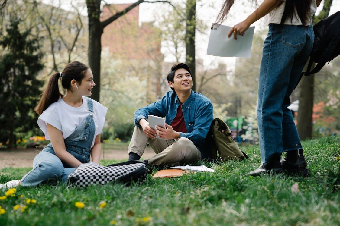A group of college students gathered on the verdant grass of a park.