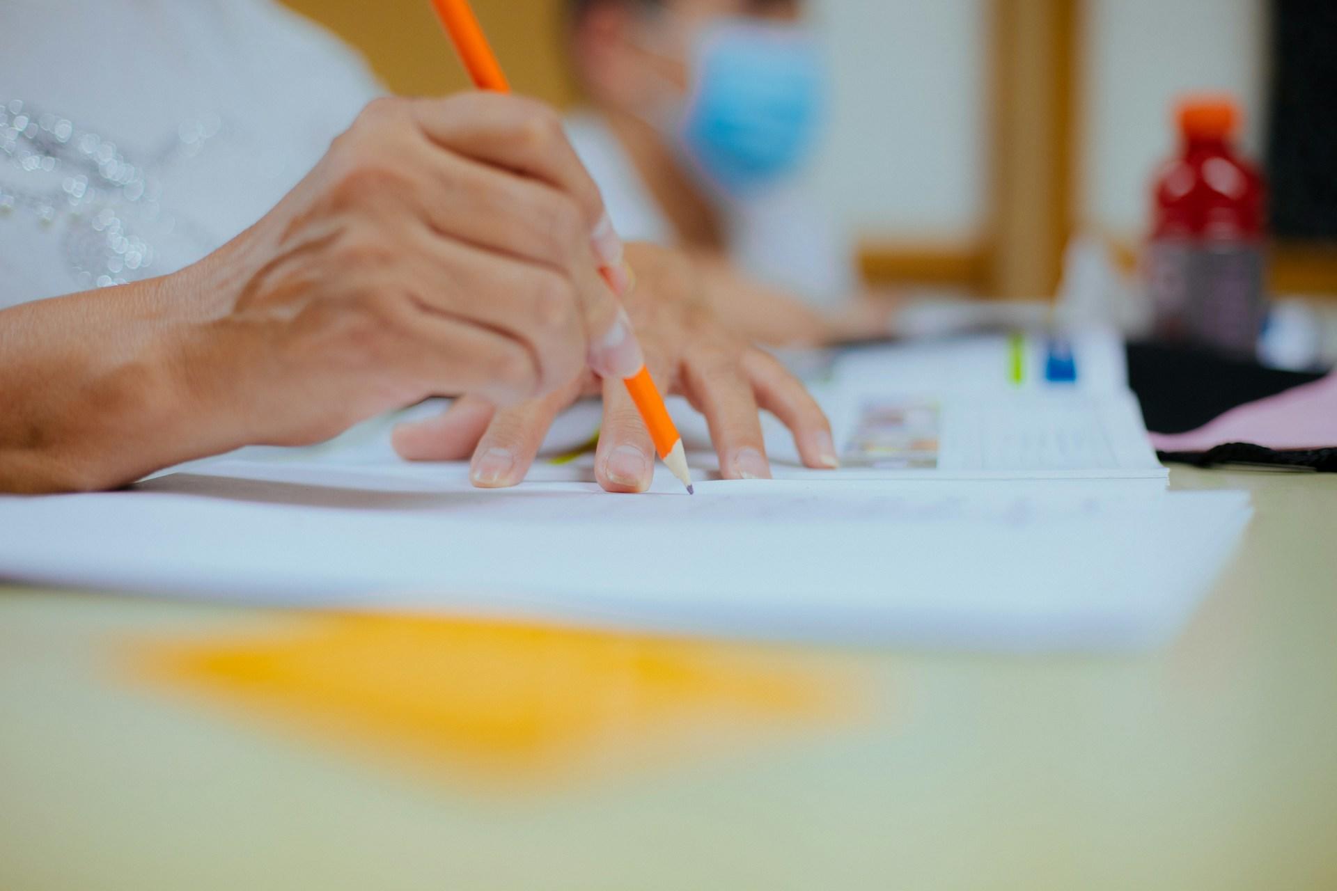 A closeup of a hand writing with a pencil.
