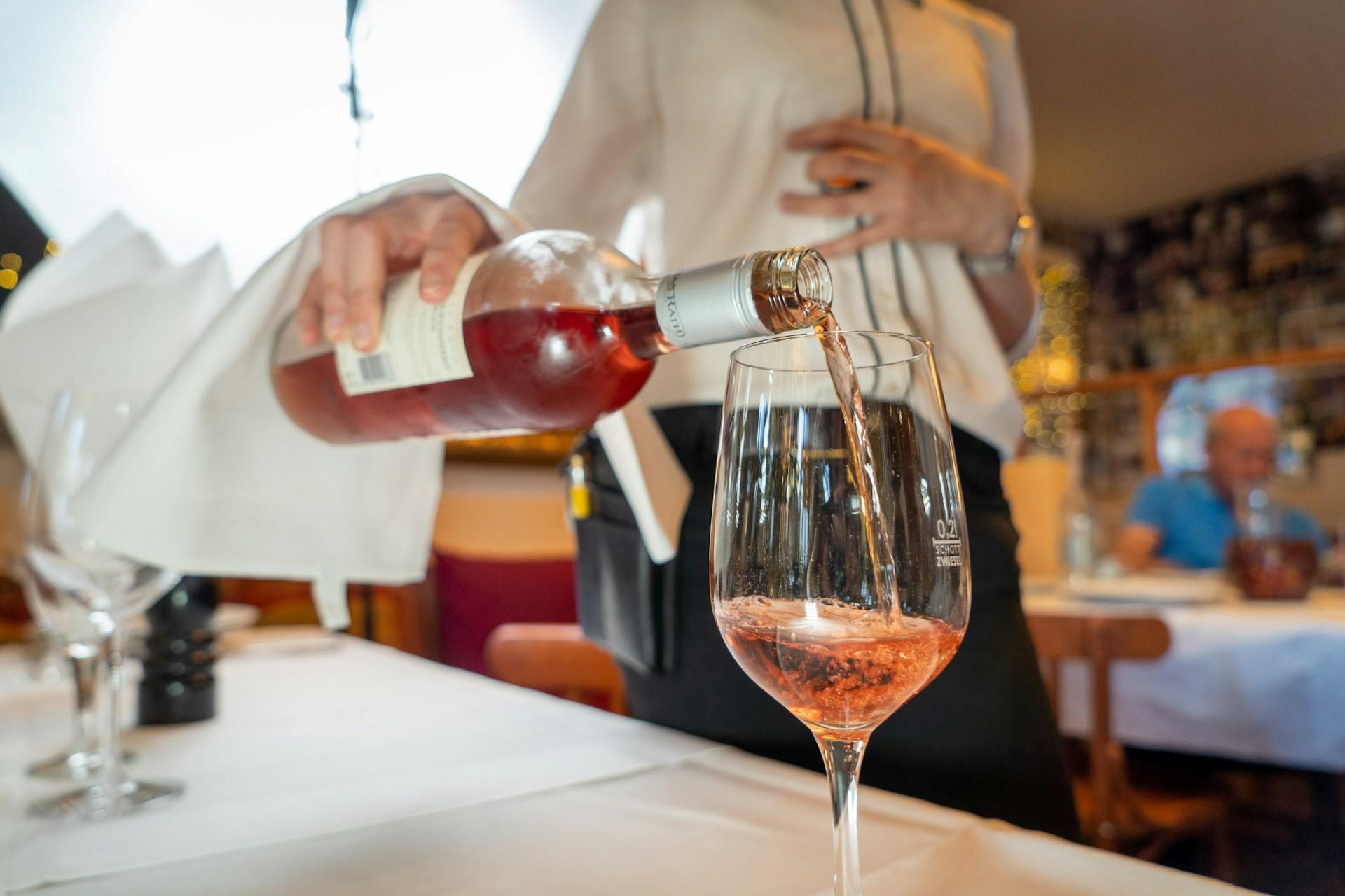 A waitress pouring a glass of rosé.