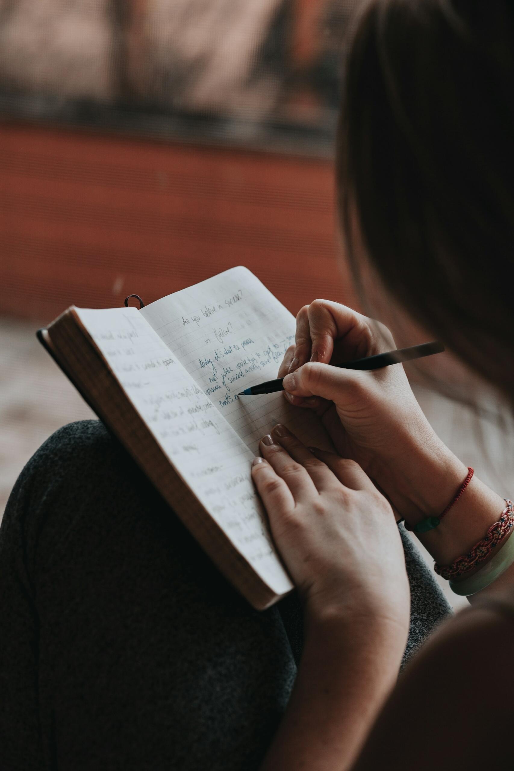 Person writing in an open notebook with a pen