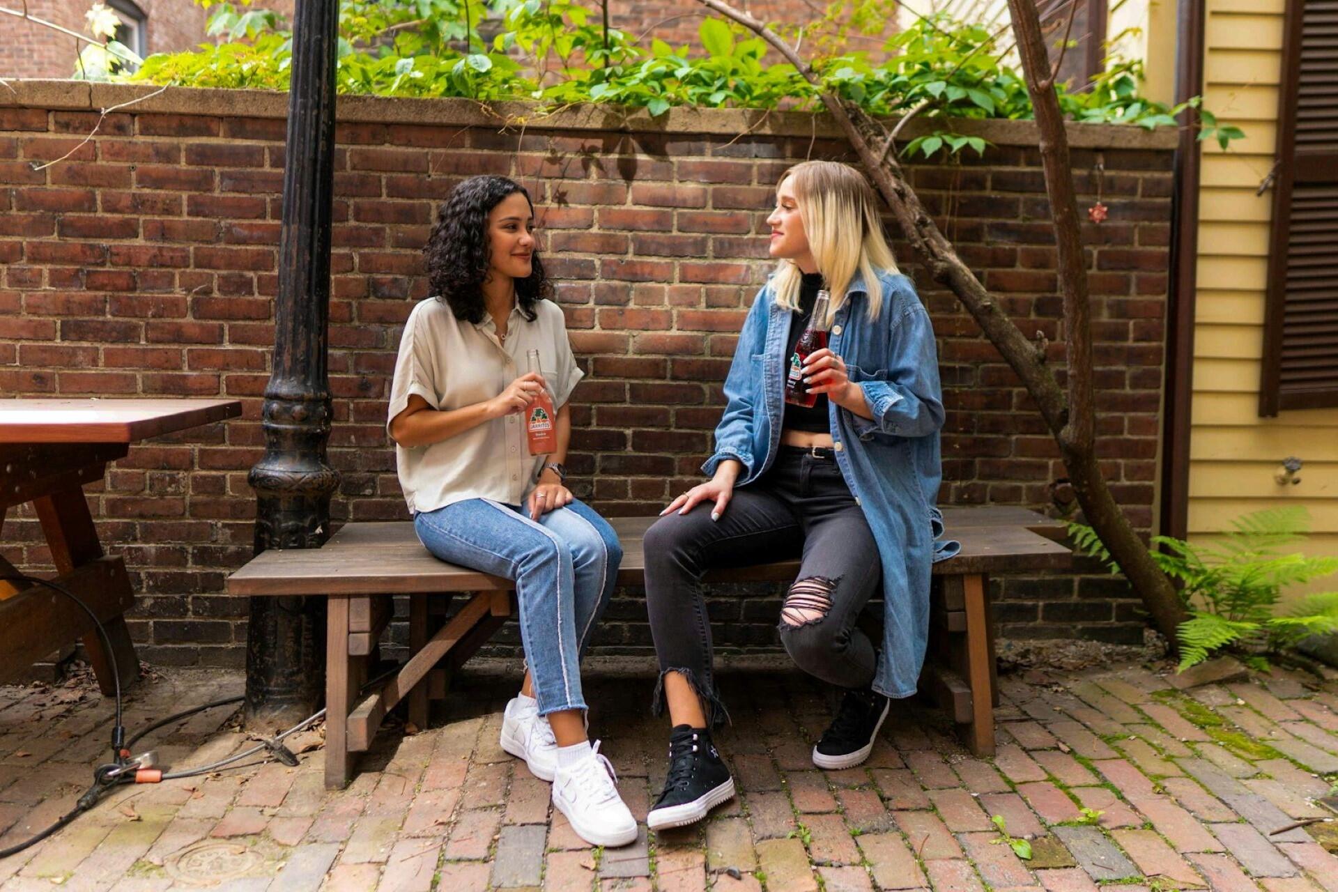 Two girls sitting on a bench talking.