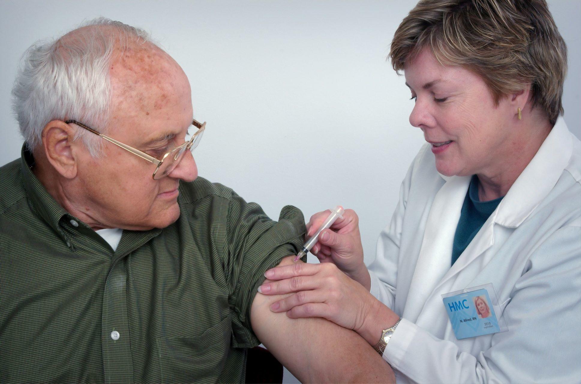 A doctor giving an elderly patient an injection.