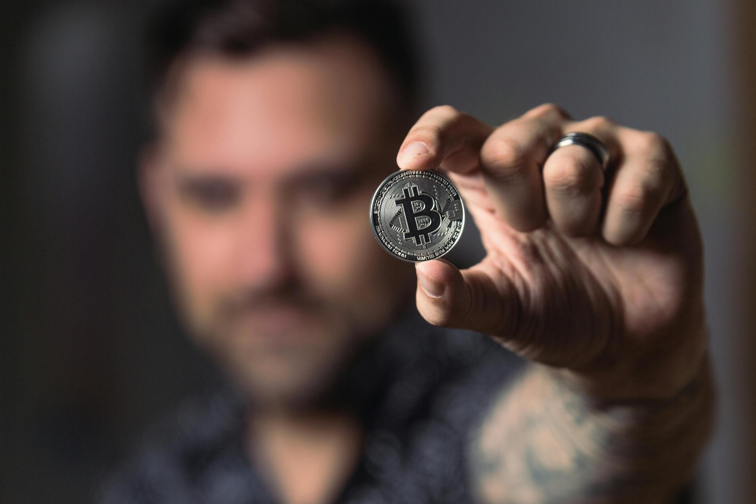 A man holding a bitcoin to the camera